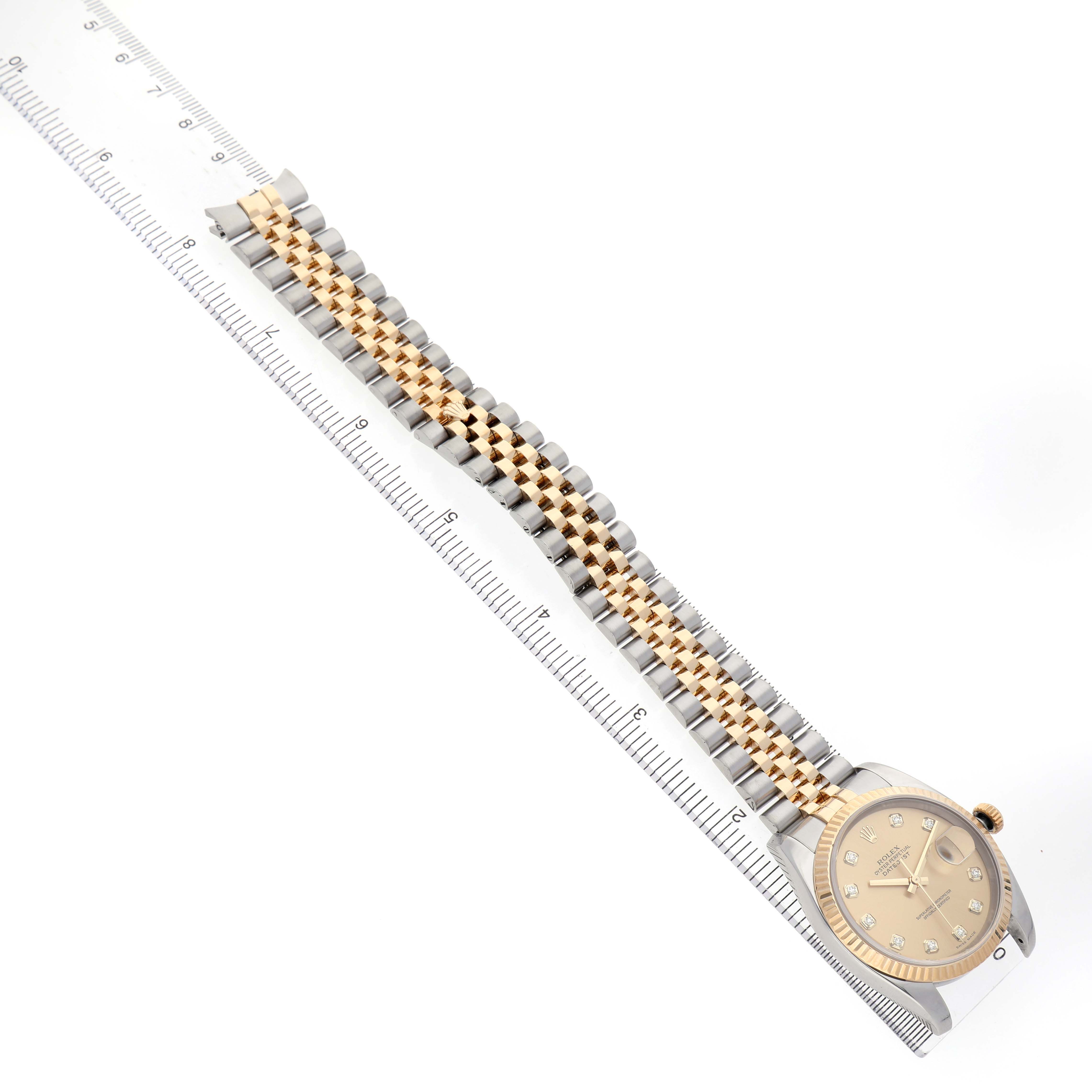 The Rolex Datejust 116233 Men's Stainless Steel Champagne Dial watch is shown from an overhead angle, displaying the full bracelet and face next to a ruler.