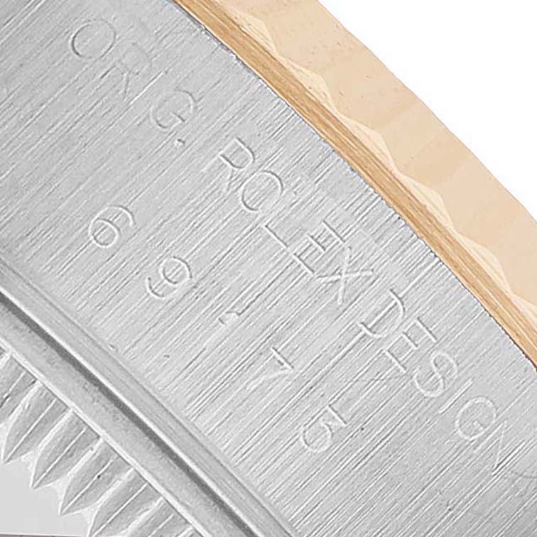This image shows a close-up of the Rolex Datejust 69173 Women's Steel and Gold (two tone) White Dial model's case side, featuring engraved text.