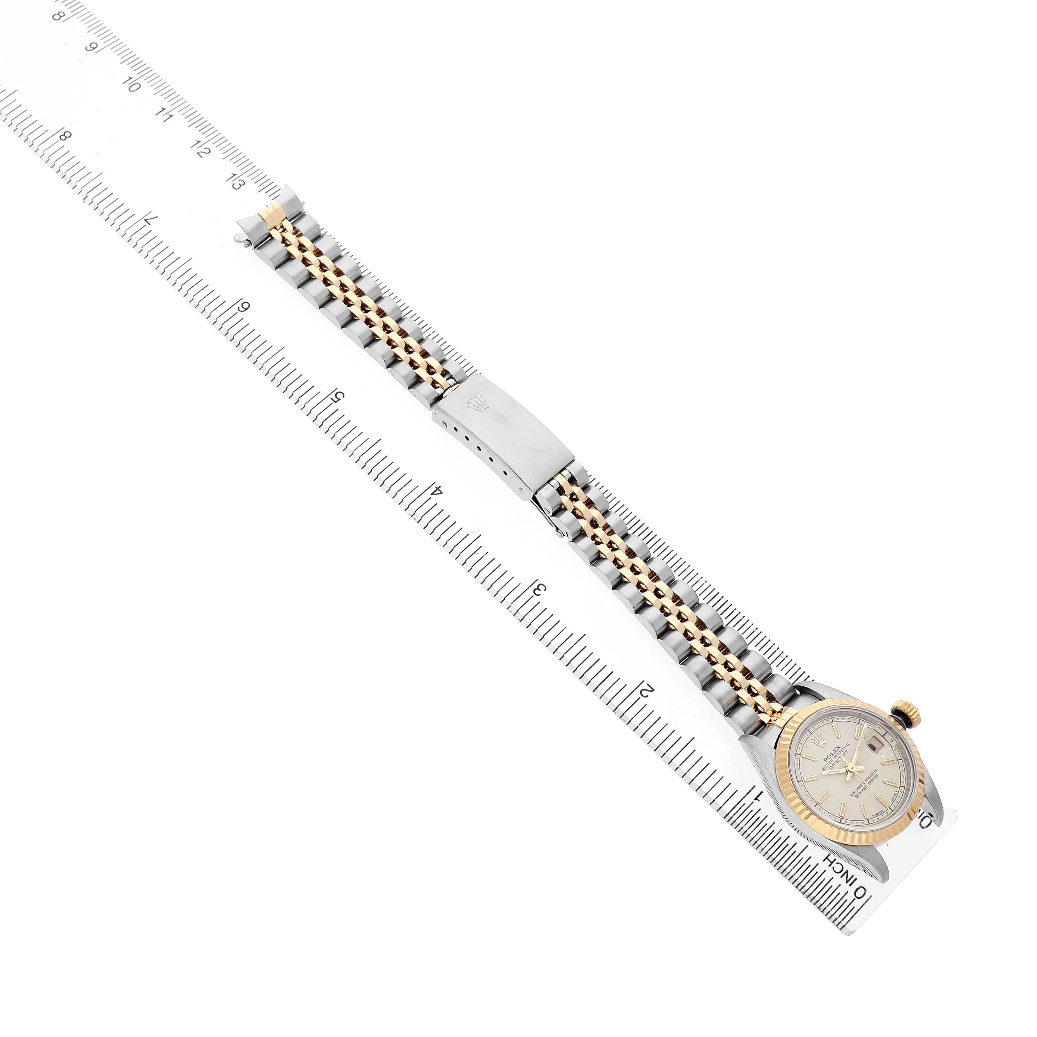 The Rolex Datejust 69173 Women's Steel and Gold (two tone) White Dial watch is shown at a diagonal angle, fully extended with its face, bracelet, and clasp visible alongside a ruler.