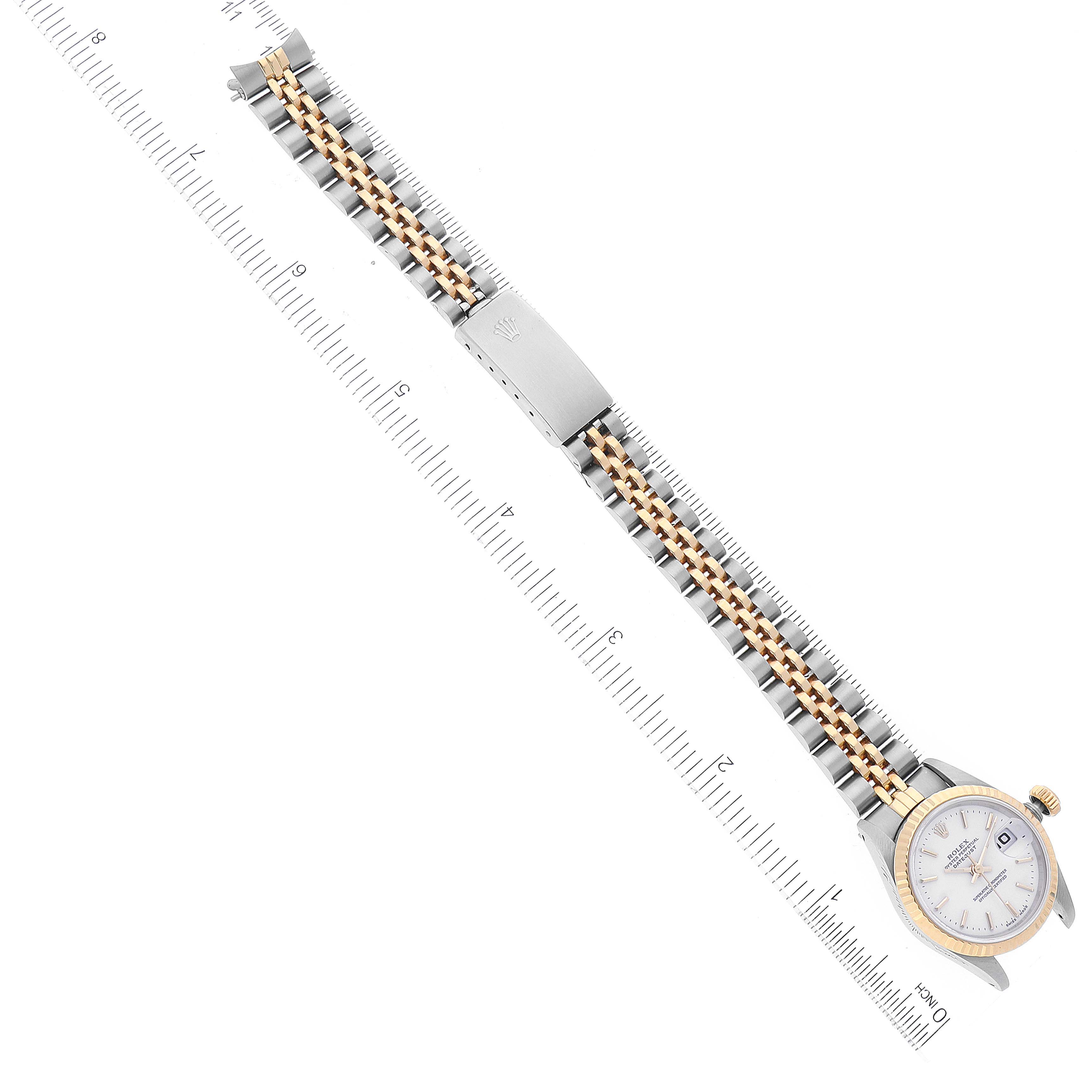 This image shows a Rolex Datejust 69173 Women
s Steel and Gold (two tone) White Dial 69173 Women
s Steel and Gold (two tone) White Dial watch laid flat with its band stretched out alongside a ruler for scale.