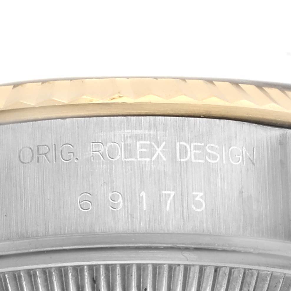 This close-up image of a Rolex Datejust 69173 Women's Steel and Gold (two tone) Blue Dial 69173 Women's Steel and Gold (two tone) Blue Dial watch shows the engraved "ORIG. ROLEX DESIGN" and model number 69173 on its case.