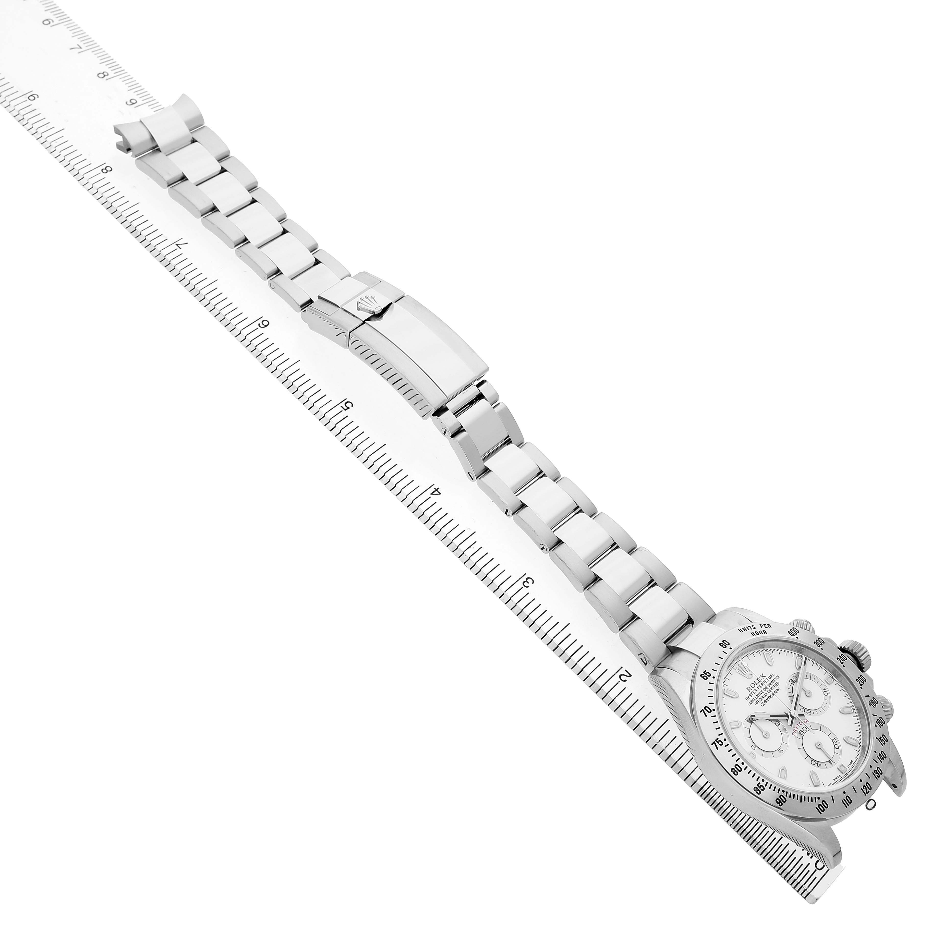 The image shows a Rolex Daytona 116520 Men's Stainless Steel White Dial watch angled diagonally, displaying the watch face, bracelet, and clasp alongside a measuring ruler.