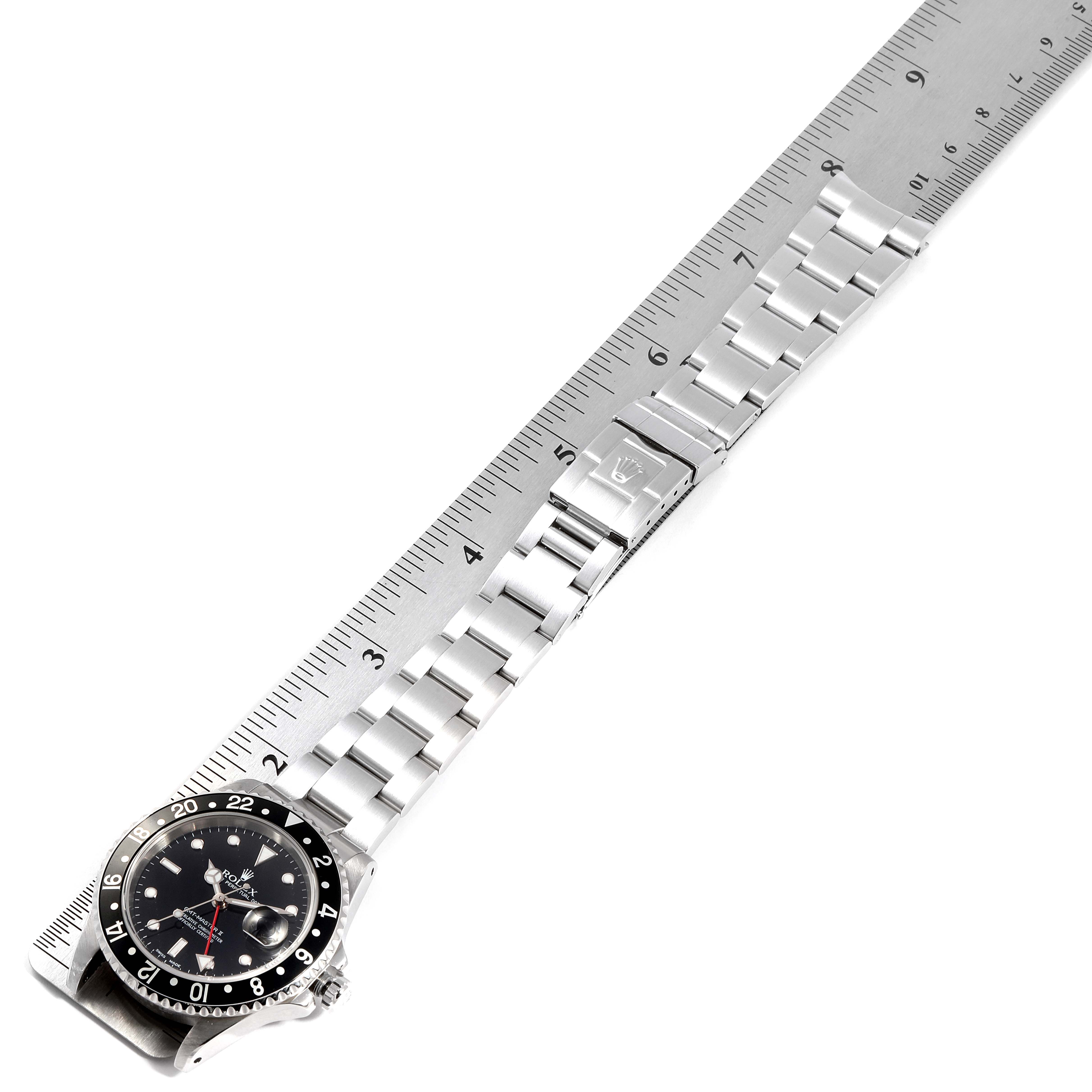 The Rolex GMT-Master 16710 Men's Stainless Steel Black Dial 16710 Men's Stainless Steel Black Dial watch is shown from above, displaying its face, bezel, and the full length of its metal bracelet alongside a ruler.