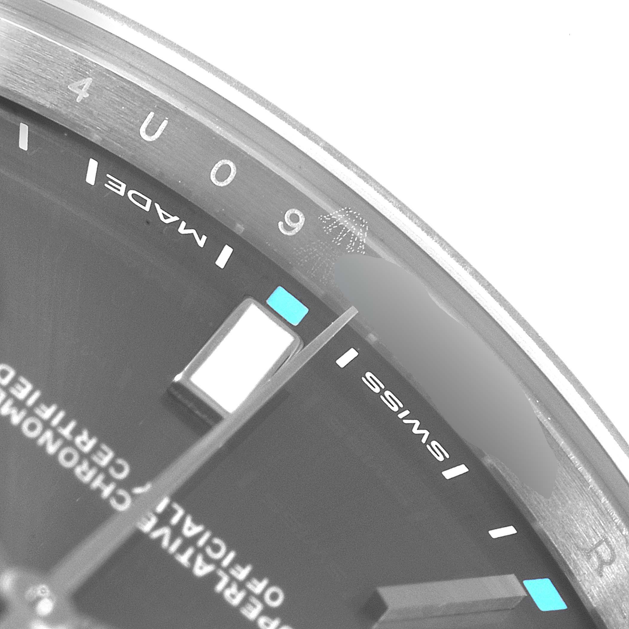 This close-up of the Rolex Oyster Perpetual 114300  Men's Stainless Steel Silver Dial 114300  Men's Stainless Steel Silver Dial watch shows the dial, indices, and part of the bezel from an oblique angle.