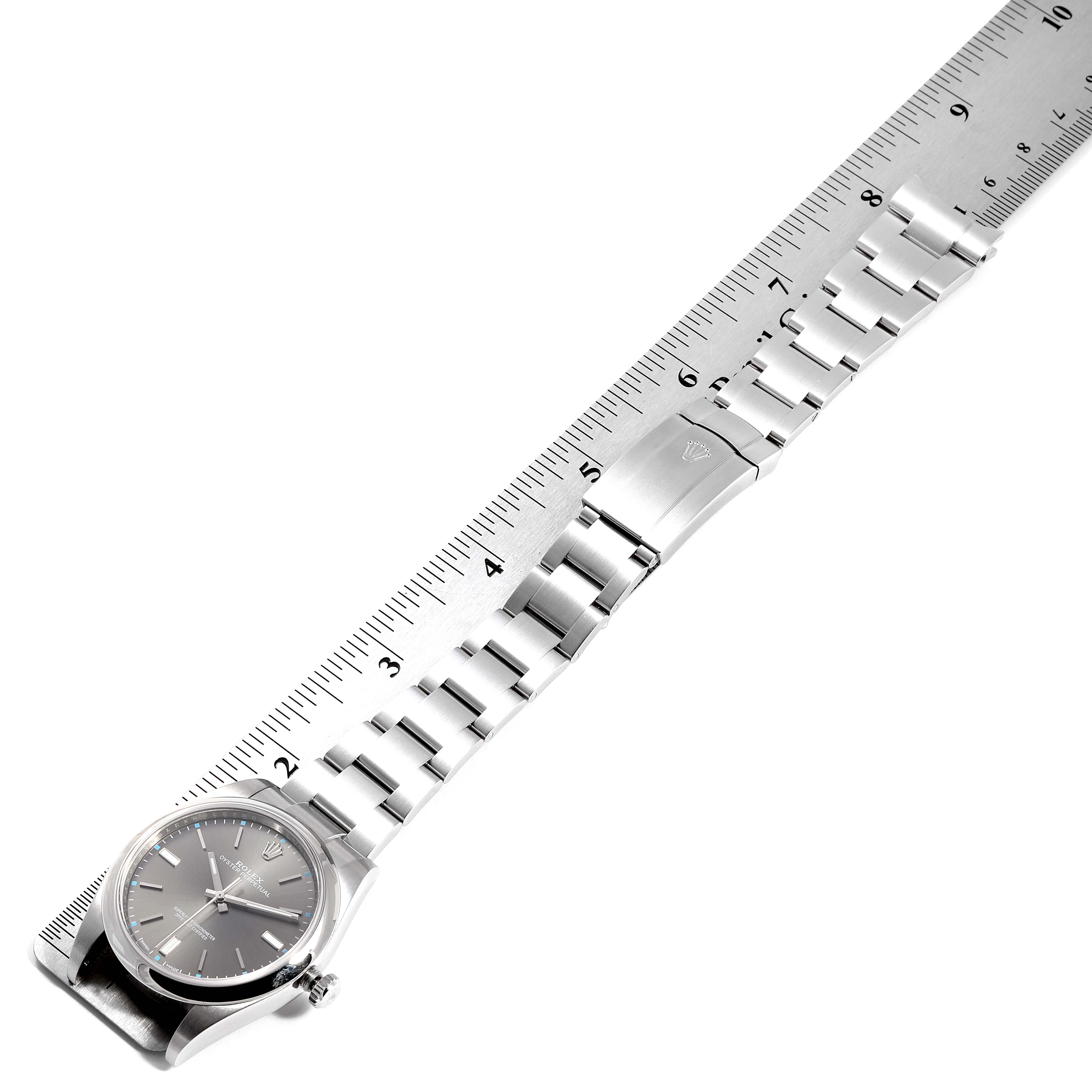 The Rolex Oyster Perpetual 114300  Men's Stainless Steel Silver Dial 114300  Men's Stainless Steel Silver Dial watch is shown from a top-down angle, including the face, bracelet, and clasp, measured against a ruler.