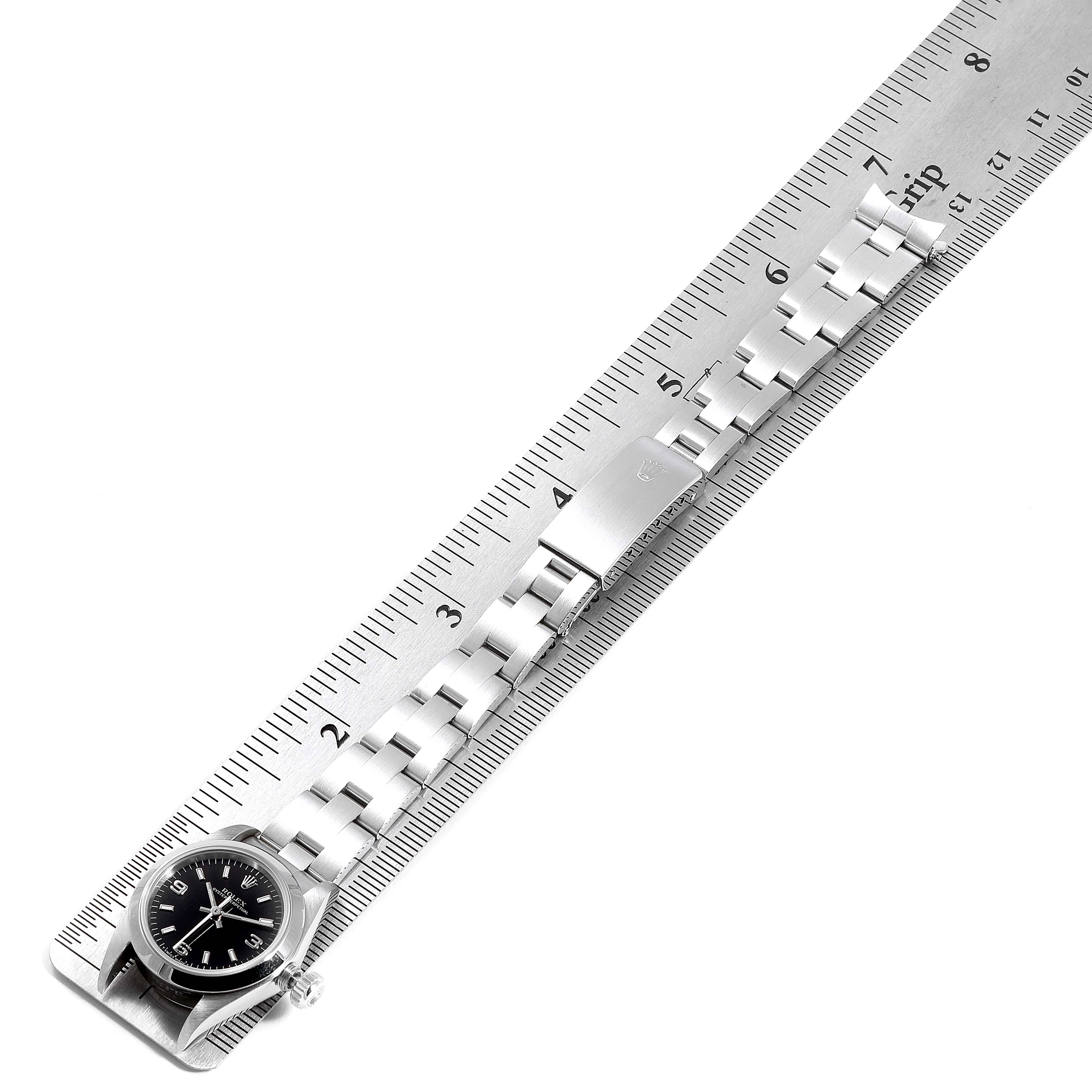 The image shows a Rolex Oyster Perpetual 67180 Women
s Stainless Steel Black Dial 67180 Women
s Stainless Steel Black Dial watch laid flat with the stainless steel bracelet and clasp visible, measured against a ruler.