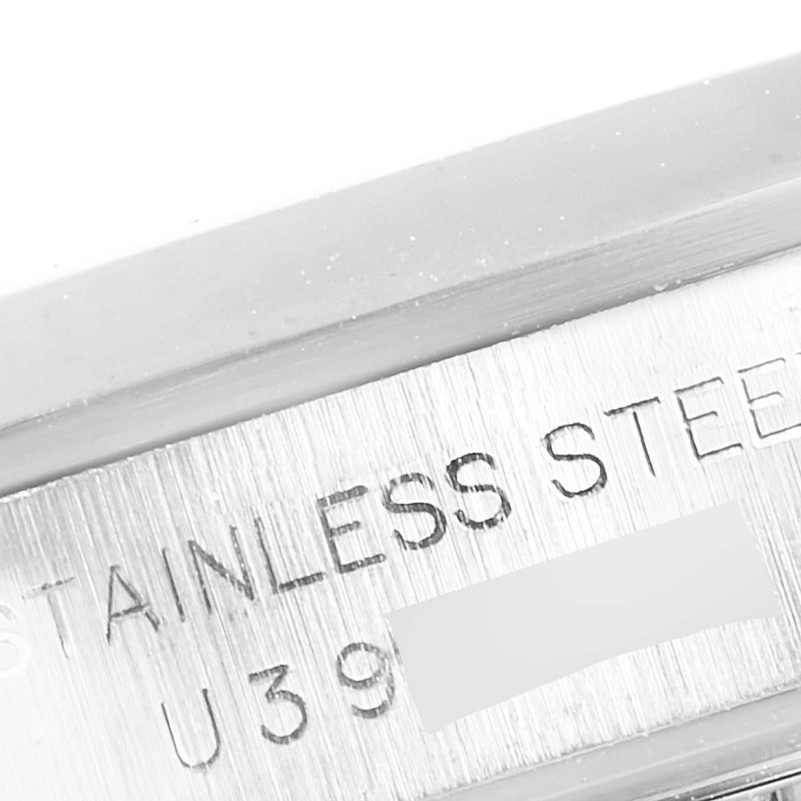 This close-up image shows the engraving of the serial number and "STAINLESS STEEL" on the side of the Rolex Oyster Perpetual 67180 Women
s Stainless Steel Black Dial 67180 Women
s Stainless Steel Black Dial watch case.