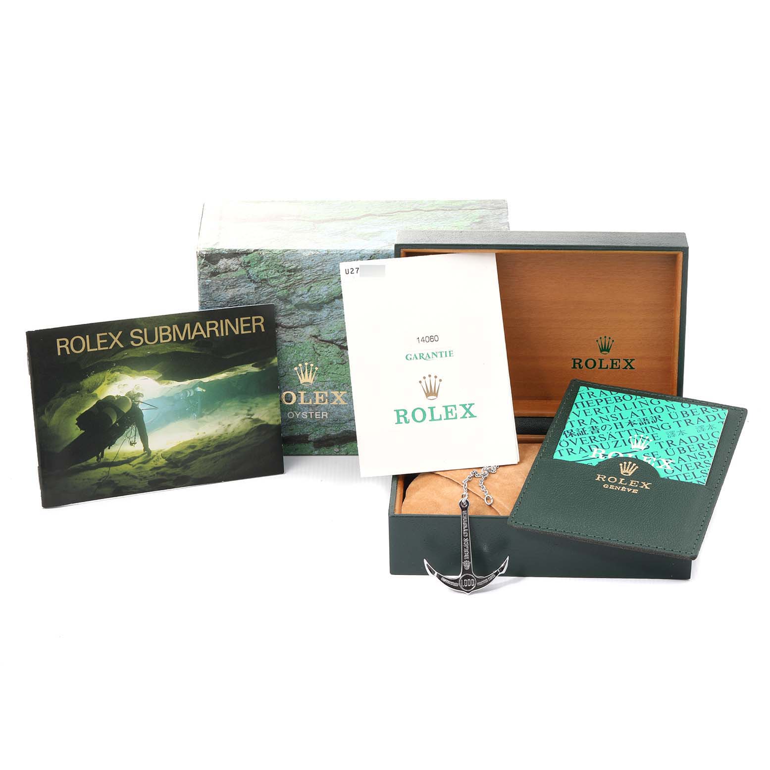 This image shows accessories for a Rolex Submariner 14060 Men's Stainless Steel Black Dial 14060 Men's Stainless Steel Black Dial watch, including a box, manuals, guarantee card, and anchor keychain.