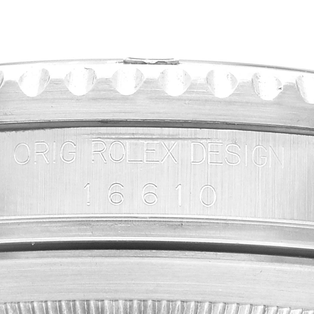Close-up of the side of a Rolex Submariner 16610 Men
s Stainless Steel Black Dial 16610 Men
s Stainless Steel Black Dial watch, showing engravings "ORIG ROLEX DESIGN 16610" beneath the bezel.