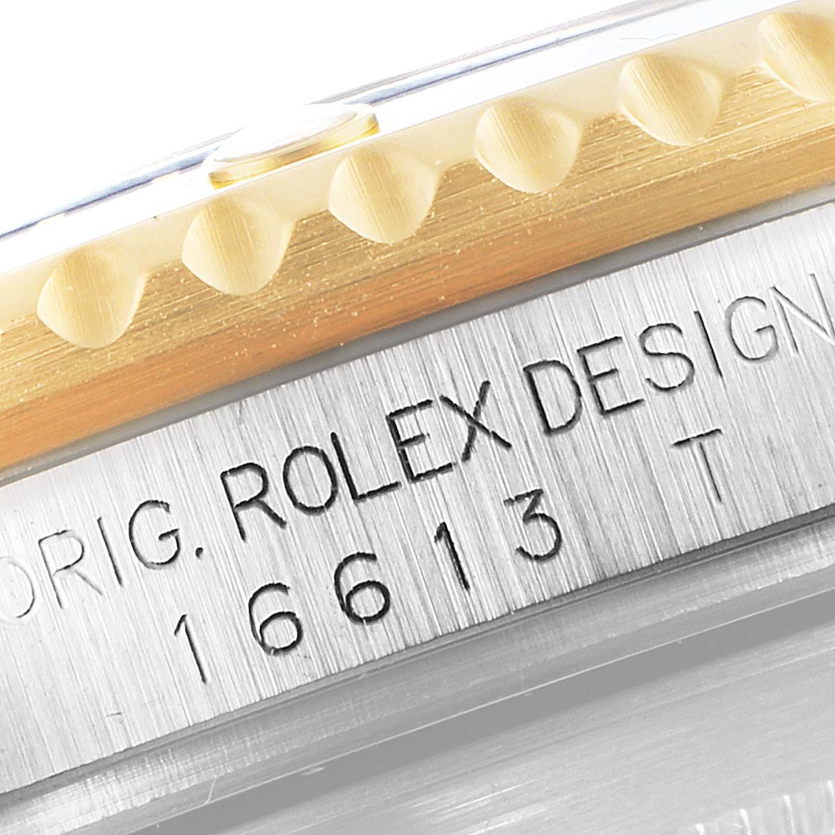 The image shows a close-up of the side of a Rolex Submariner 16613 Men
s Steel and Gold (two tone) Blue Dial 16613 Men
s Steel and Gold (two tone) Blue Dial watch, focusing on the engraving and bezel edge.