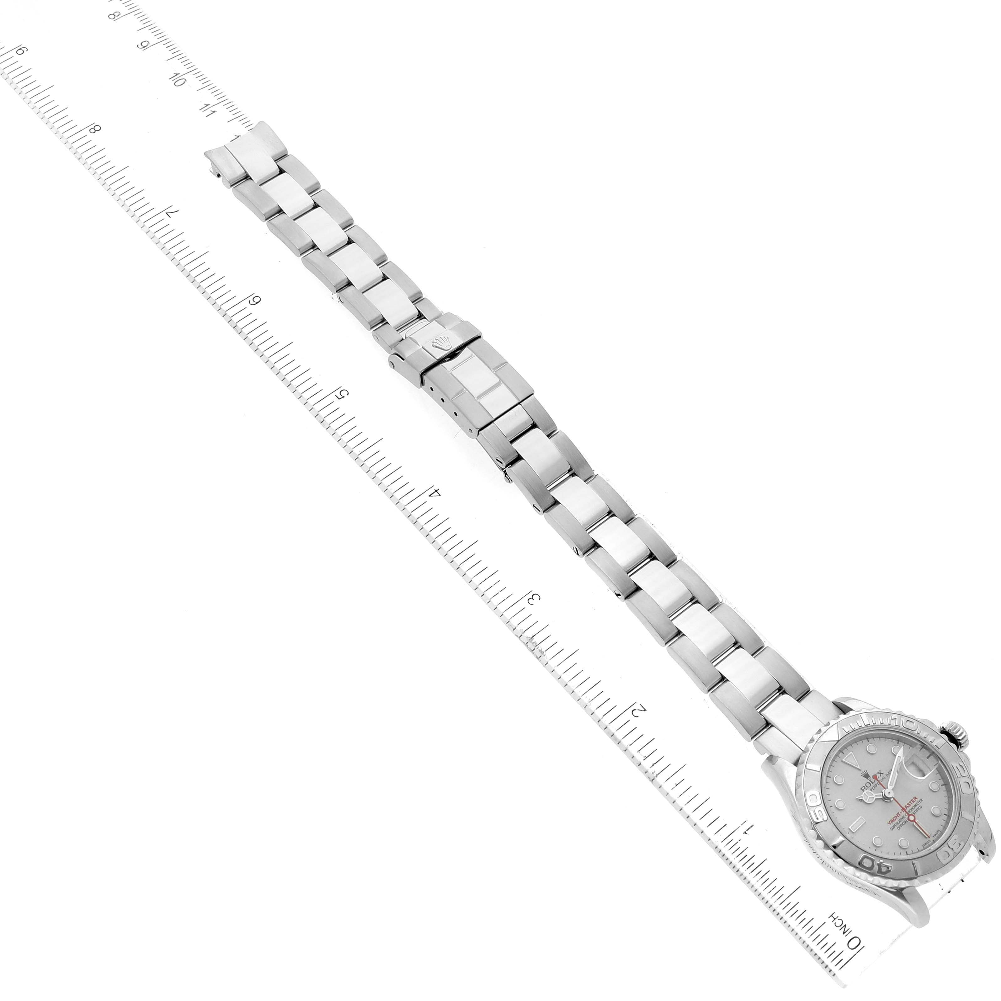 The image shows a Rolex Yacht-Master 169622 Women
s Stainless Steel Silver Dial 169622 Women
s Stainless Steel Silver Dial watch with its band fully extended, placed along a measuring ruler.