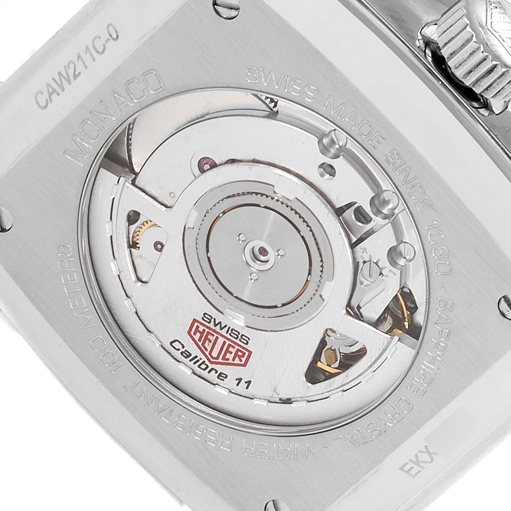 The image shows the back view of a Tag Heuer Monaco watch, featuring its internal mechanism and engraving details.