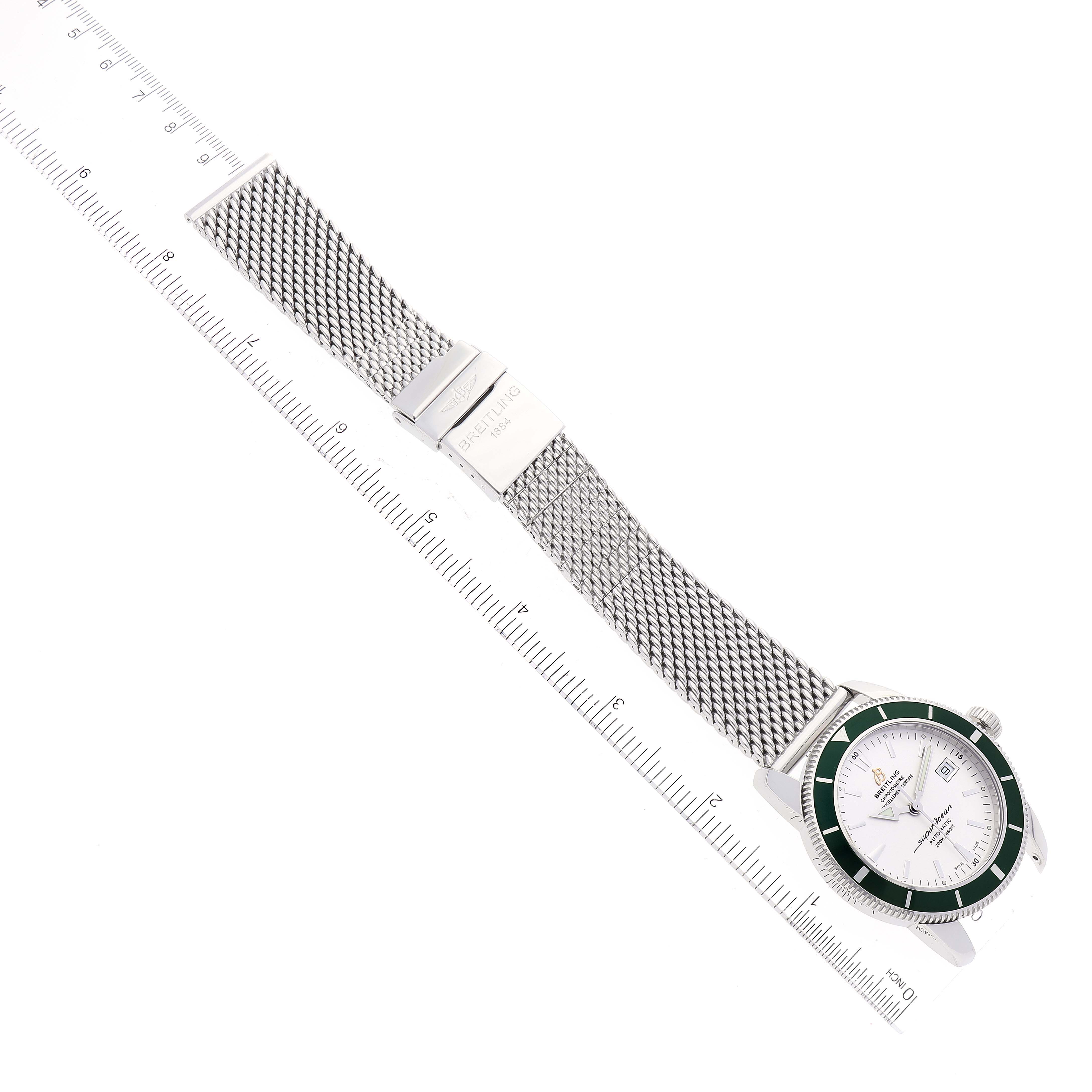The image shows a top-down view of a Breitling Superocean A17321 Men's Stainless Steel White Dial A17321 Men's Stainless Steel White Dial watch with a mesh band and a ruler for measurement.