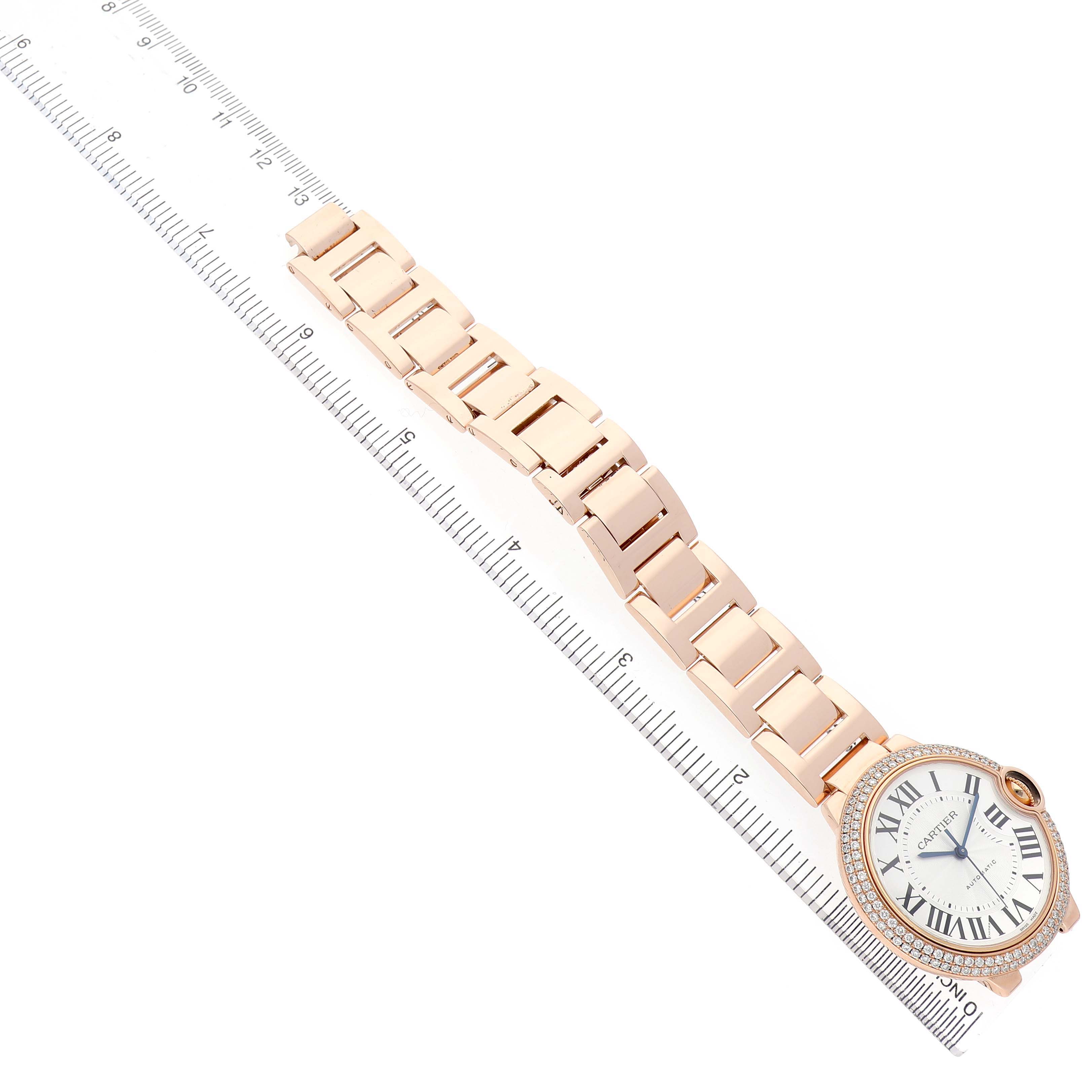 The Cartier Ballon Bleu WE9005Z3 Women's Rose Gold Silver Dial watch is shown from an angled top view, displaying the bracelet and face with a ruler beside it.