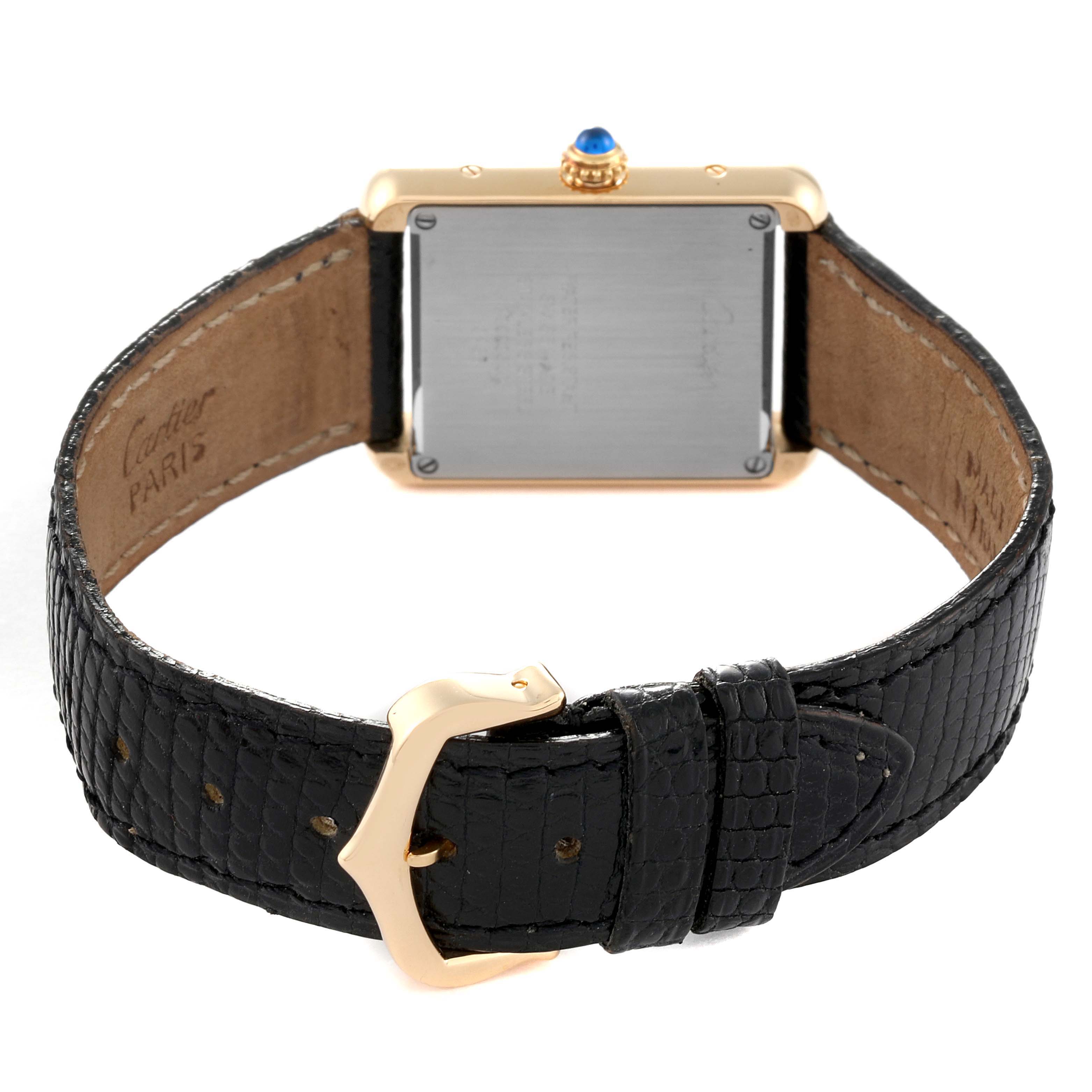 The image shows the back view of a Cartier Tank Solo W5200002 Men
s Yellow Gold Silver Dial W5200002 Men
s Yellow Gold Silver Dial watch, highlighting its case, blue crown, and black leather strap with gold-tone buckle.