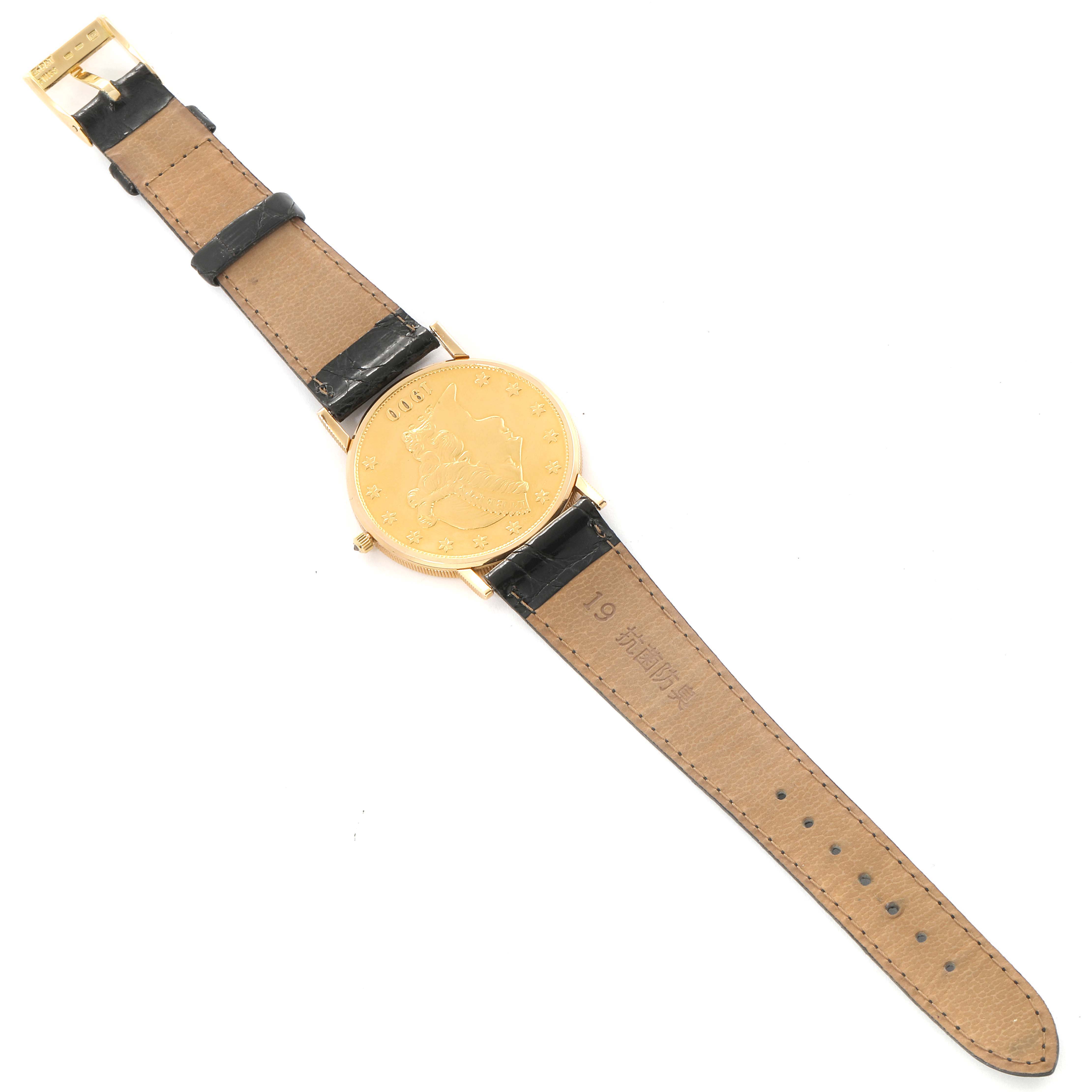 The image shows a Corum Coin Watch 1900 Men's Yellow Gold Black Dial 1900 Men's Yellow Gold Black Dial model placed face-up, displaying the straps and the coin-themed dial.