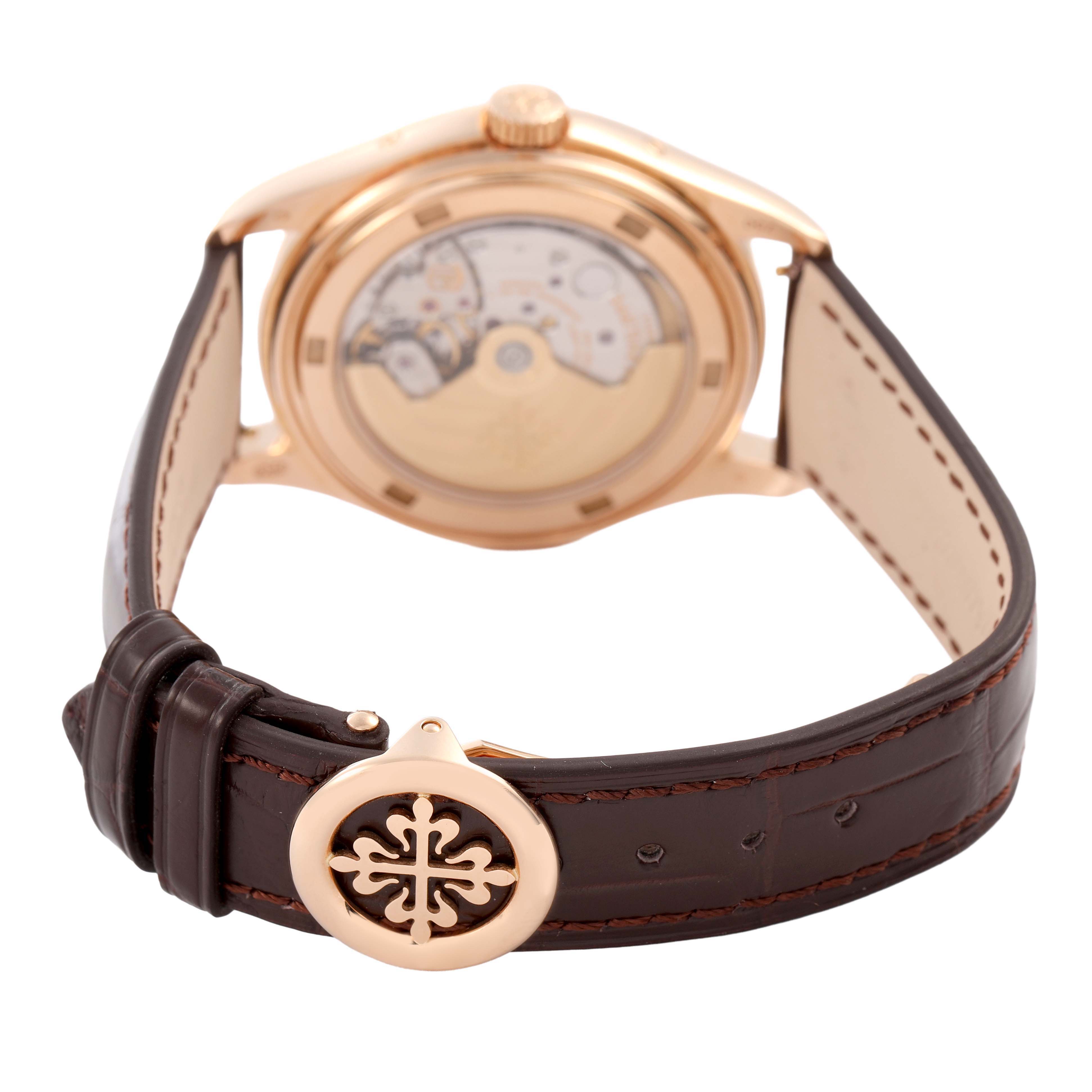 The Patek Philippe Complications 5146R-001 Men's Rose Gold White Dial watch is shown from the back, highlighting the transparent case back and leather strap with a decorative clasp.