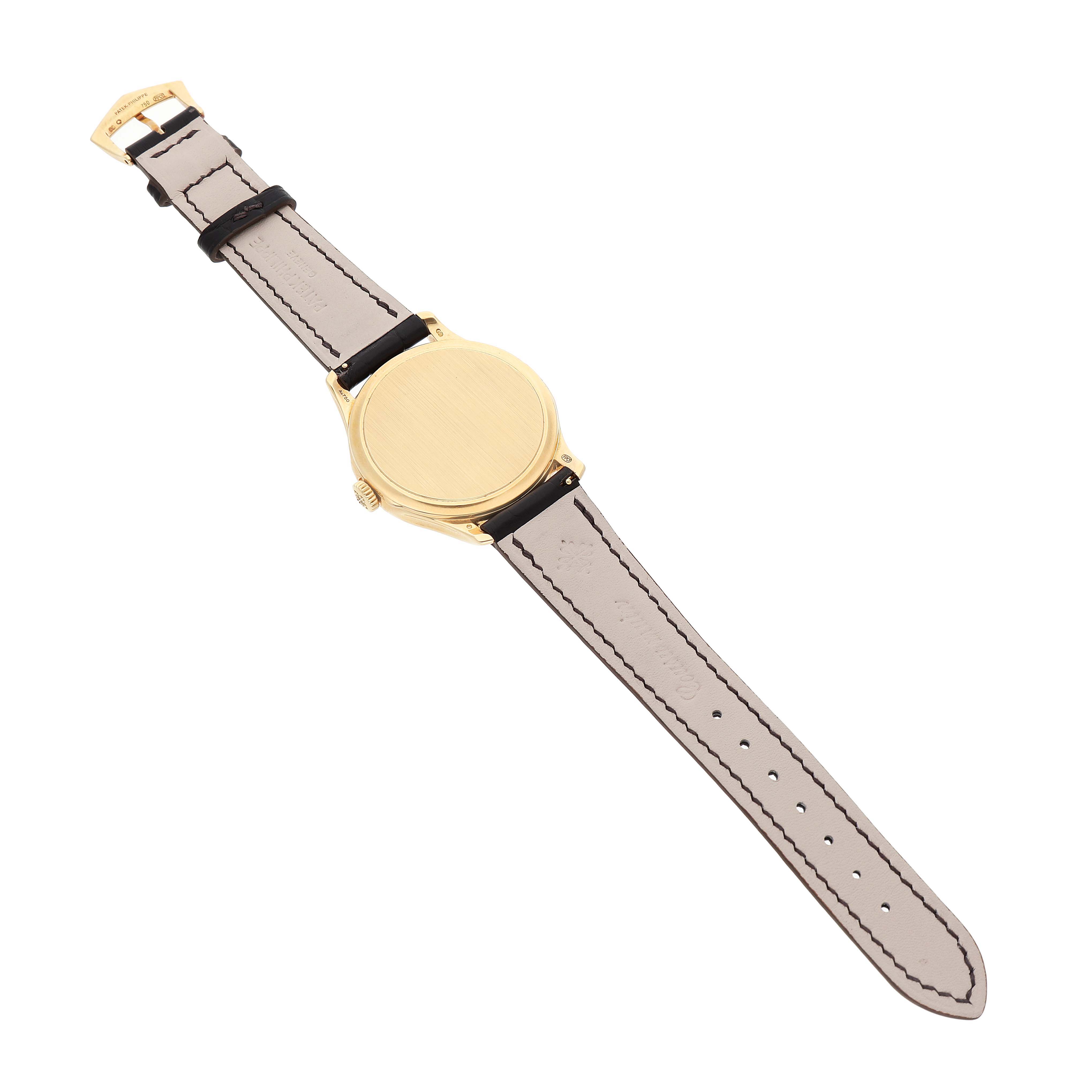 The Patek Philippe Calatrava 5227J Men's Yellow Gold White Dial watch is shown from the back, displaying the closed case back and leather strap.