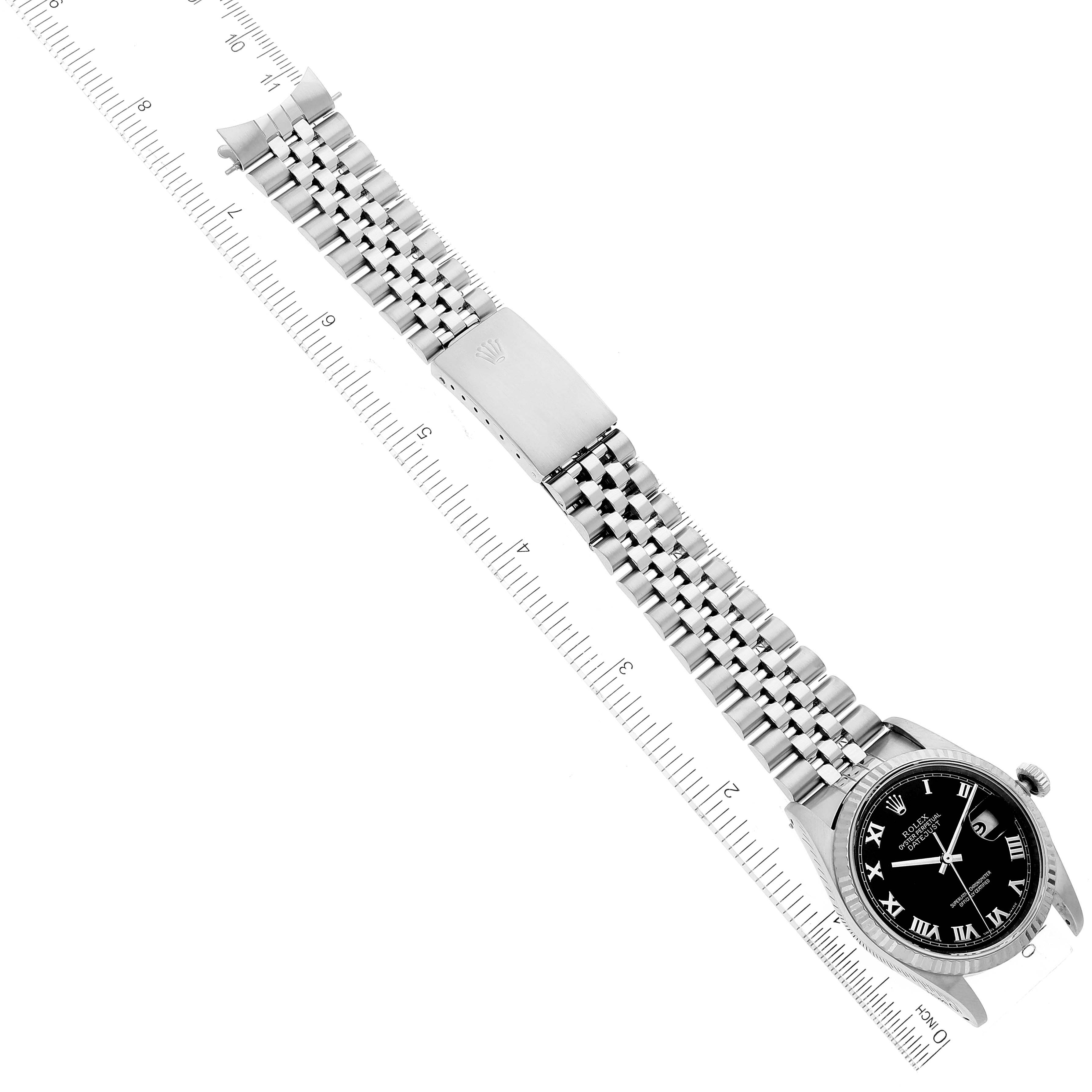 The image shows a Rolex Datejust 16234 Men's Stainless Steel Black Dial 16234 Men's Stainless Steel Black Dial watch placed diagonally with its bracelet and clasp fully extended next to a ruler for scale.