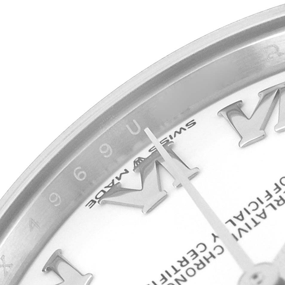 This close-up of a Rolex Mid-Size 278274 Women
s Stainless Steel White Dial 278274 Women
s Stainless Steel White Dial watch shows the bezel, part of the face, Roman numerals, and the minute hand.