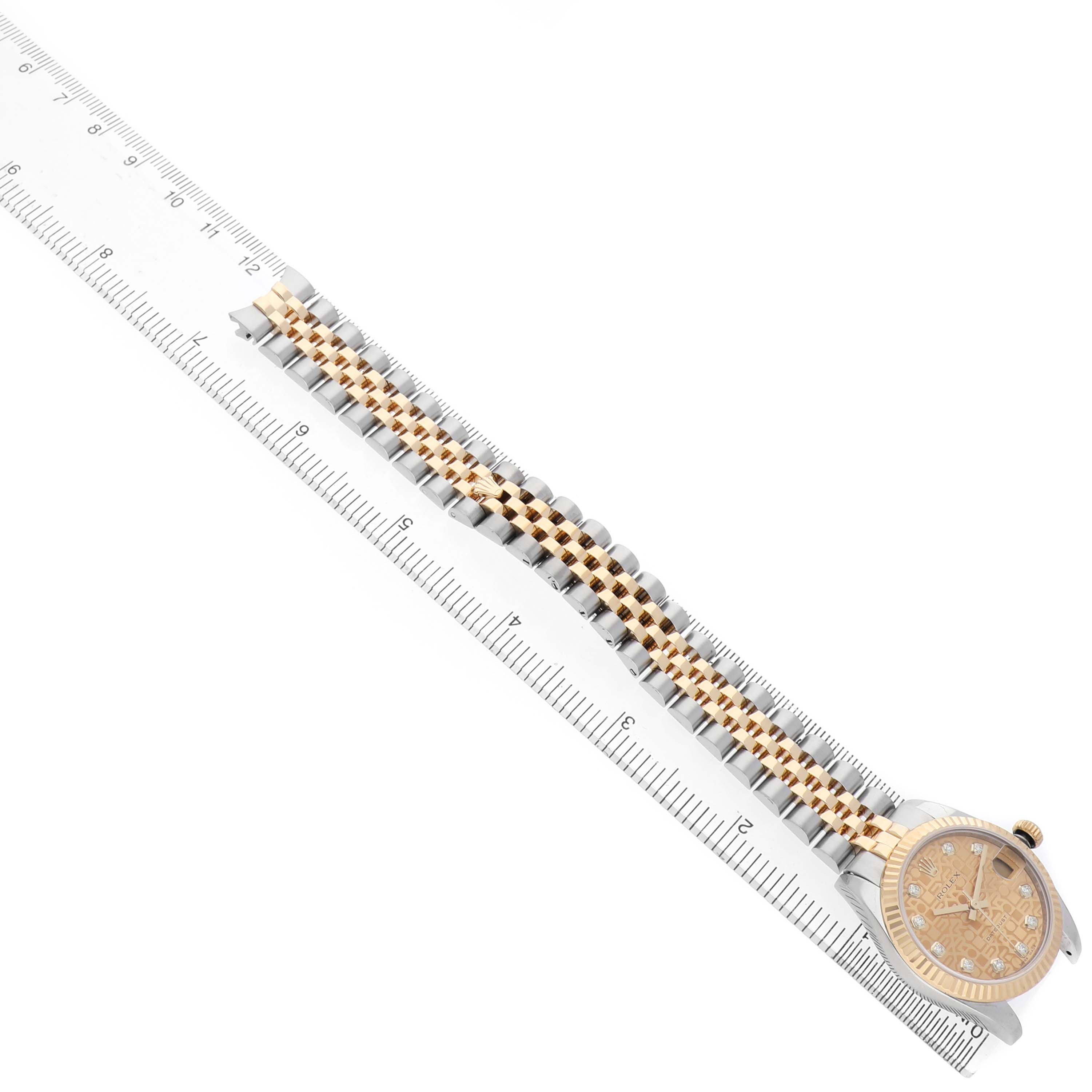 The Rolex Mid-Size 178273 Women's Steel and Gold (two tone) Champagne Dial watch is shown at an angle displaying the full band and face, with a ruler for scale.