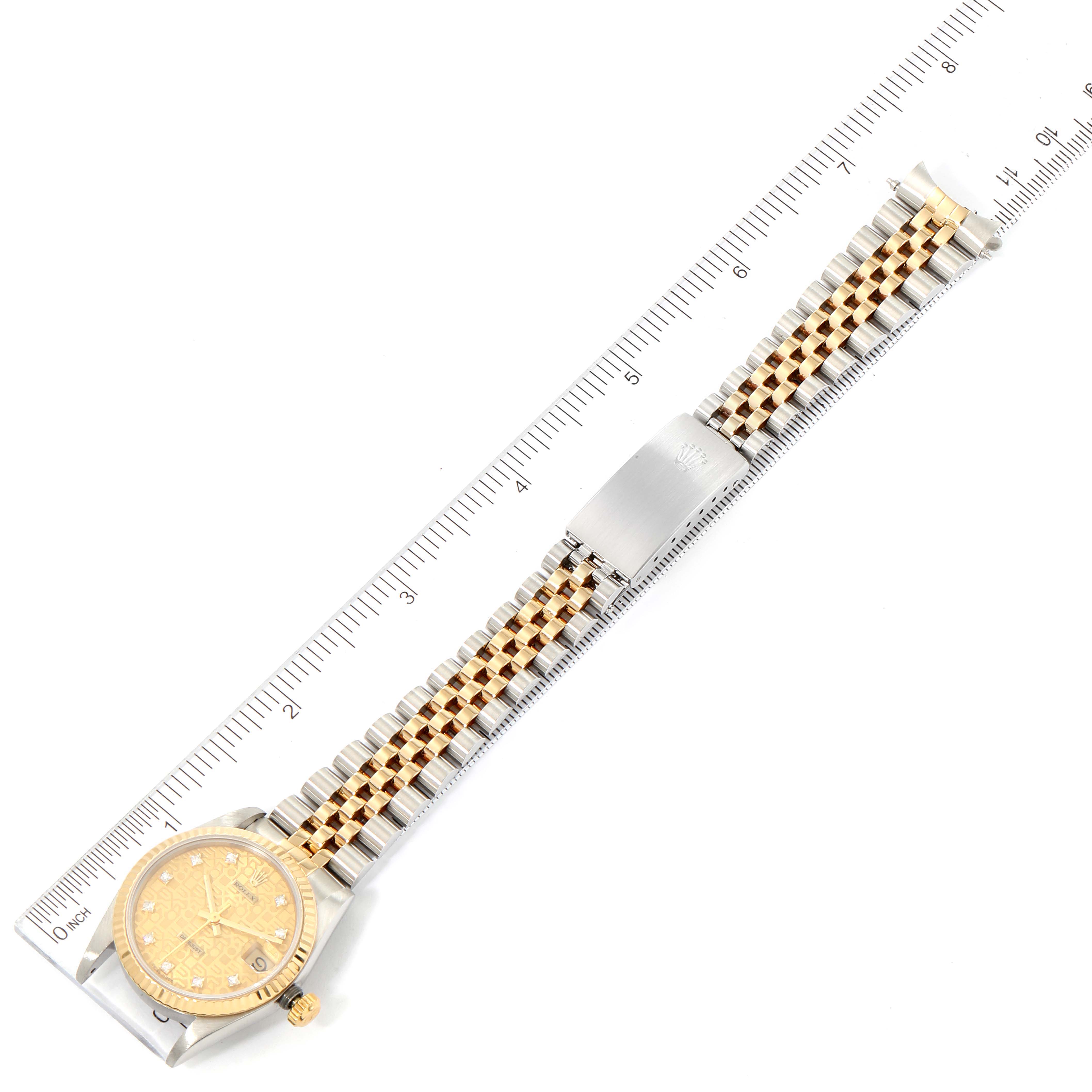 Displayed flat, this Mid-Size Rolex watch shows the dial, bezel, bracelet, and clasp alongside a ruler for scale.