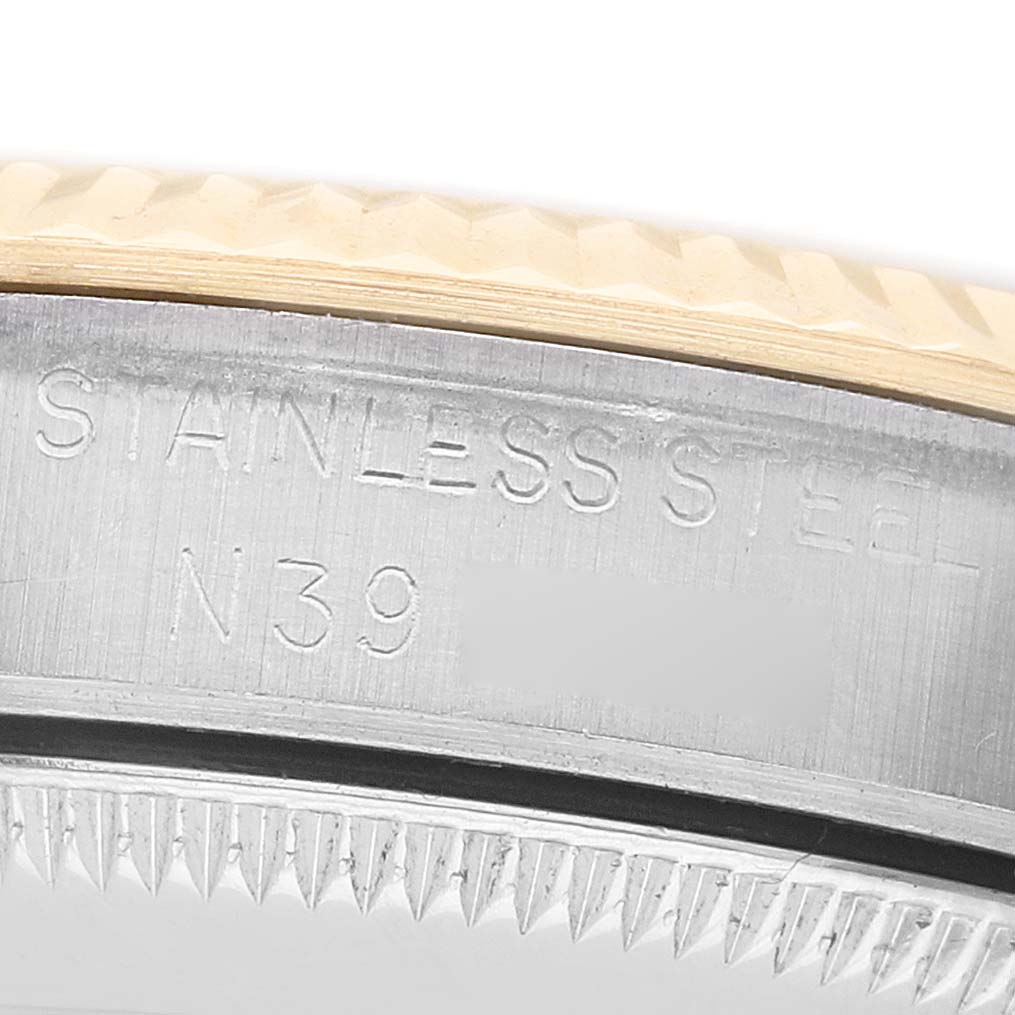 The image shows a detailed close-up of the bezel and case edge of a mid-size Rolex watch, focusing on the stainless steel engraving.