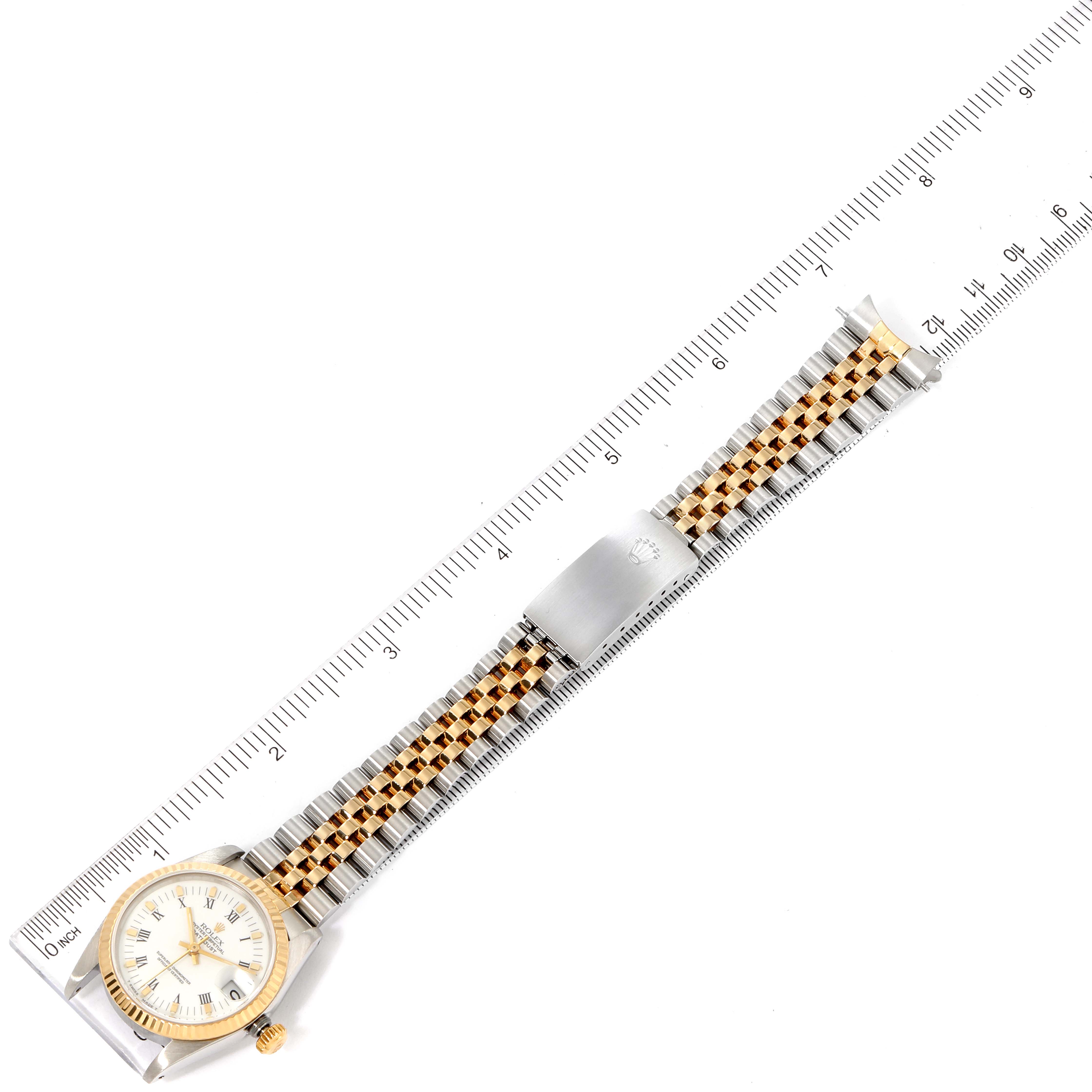 A Mid-Size Rolex watch is shown from a top-down angle, displaying its face, bezel, and two-tone bracelet alongside a ruler for scale.