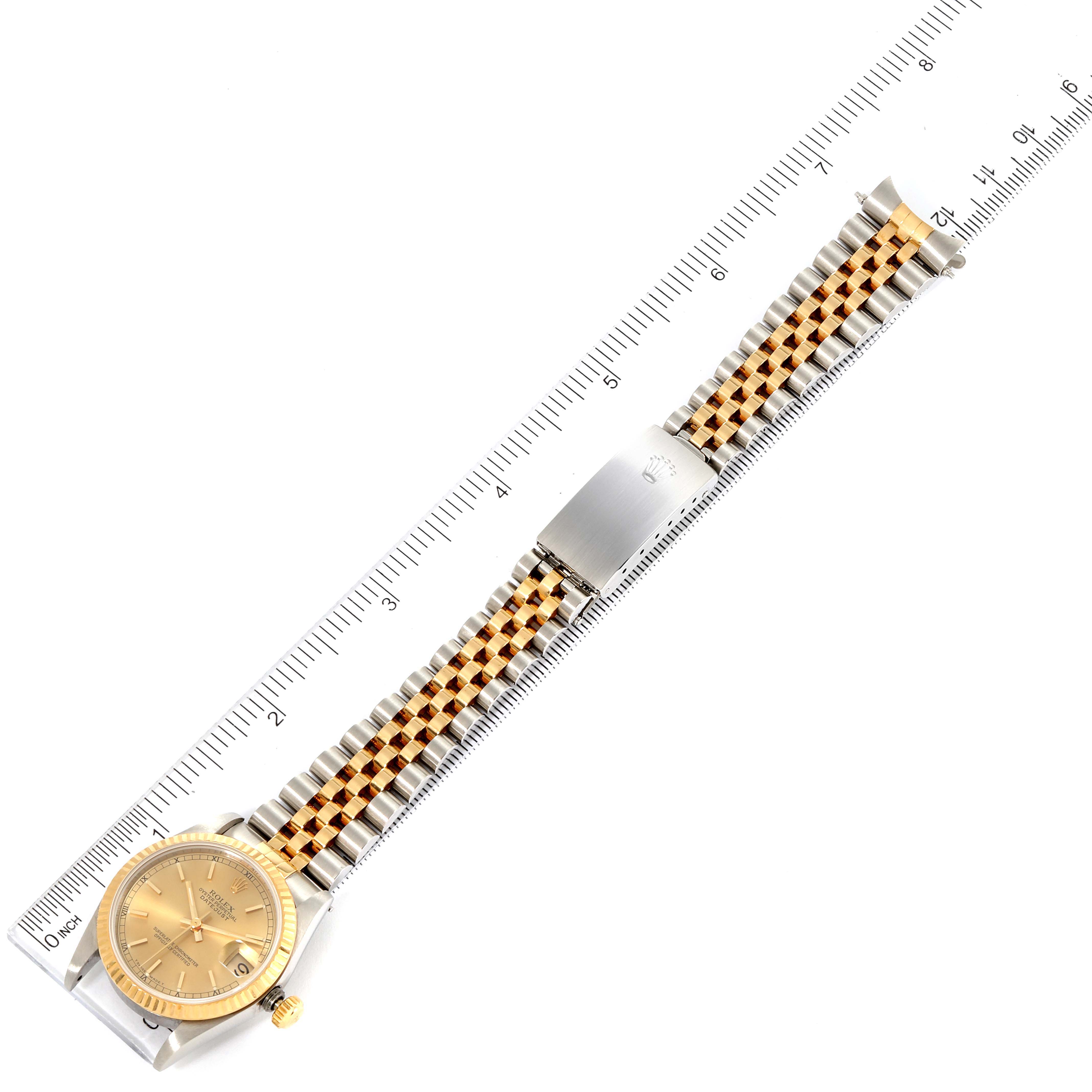 The image shows a top-down view of a Mid-Size Rolex watch with a gold-tone dial and a two-tone bracelet positioned alongside a measuring ruler.
