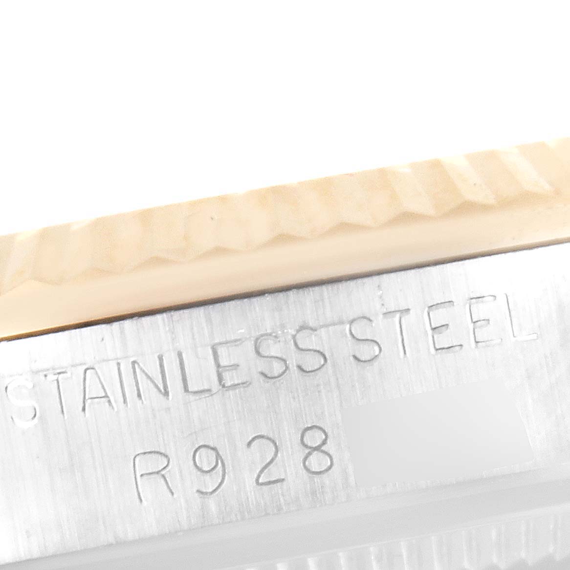 The image shows a close-up of the stainless steel case back and fluted bezel of a mid-size Rolex watch.