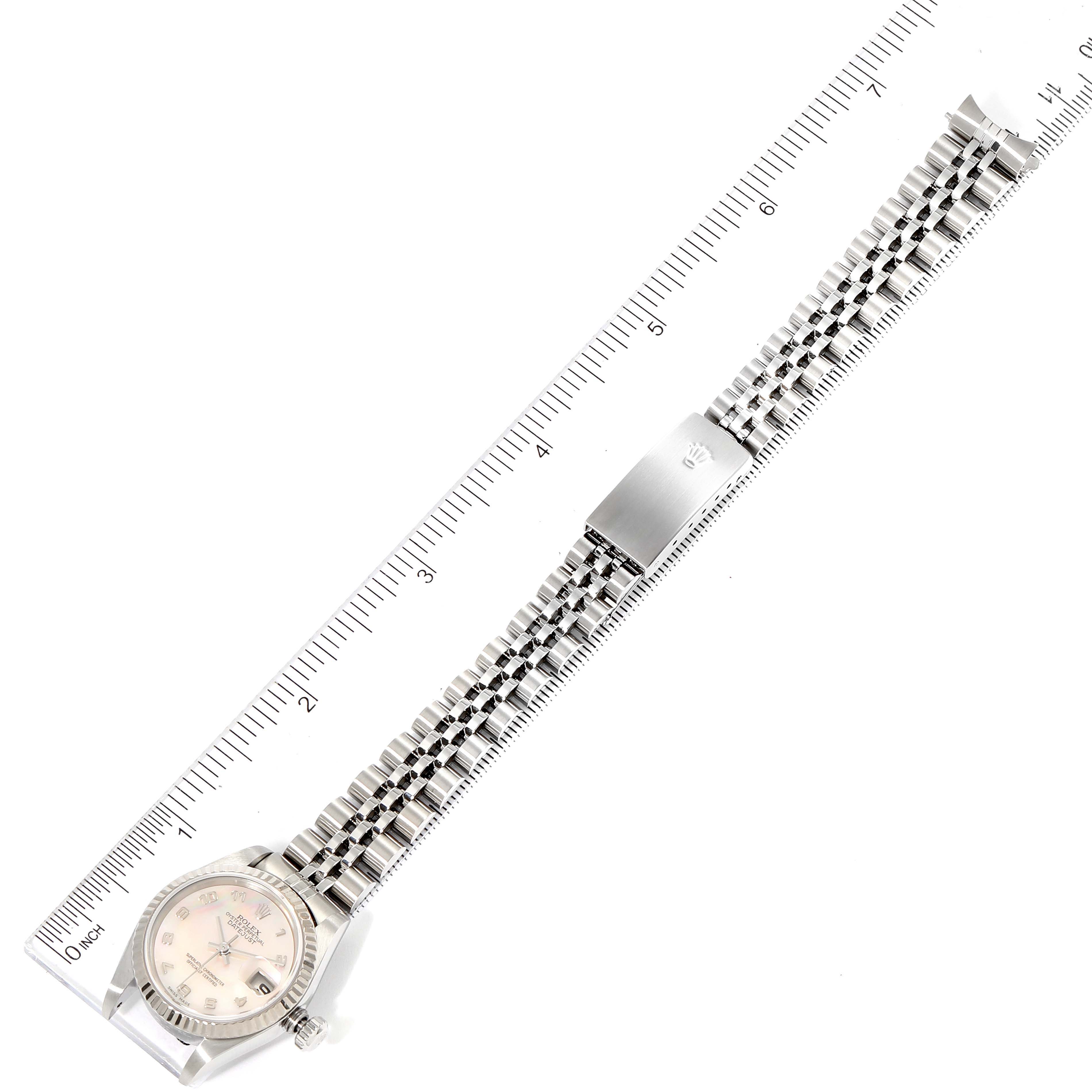 The Rolex Datejust 79174 Women
s Stainless Steel Mother of Pearl Dial 79174 Women
s Stainless Steel Mother of Pearl Dial watch is shown in a top-down view, displaying the full bracelet extended next to a ruler.