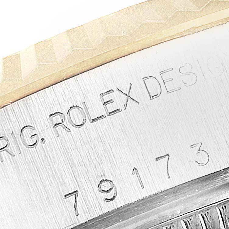 The image shows a close-up of the side engraving and part of the bezel of a Rolex Datejust 79173 Women
s Steel and Gold (two tone) White Dial 79173 Women
s Steel and Gold (two tone) White Dial watch.