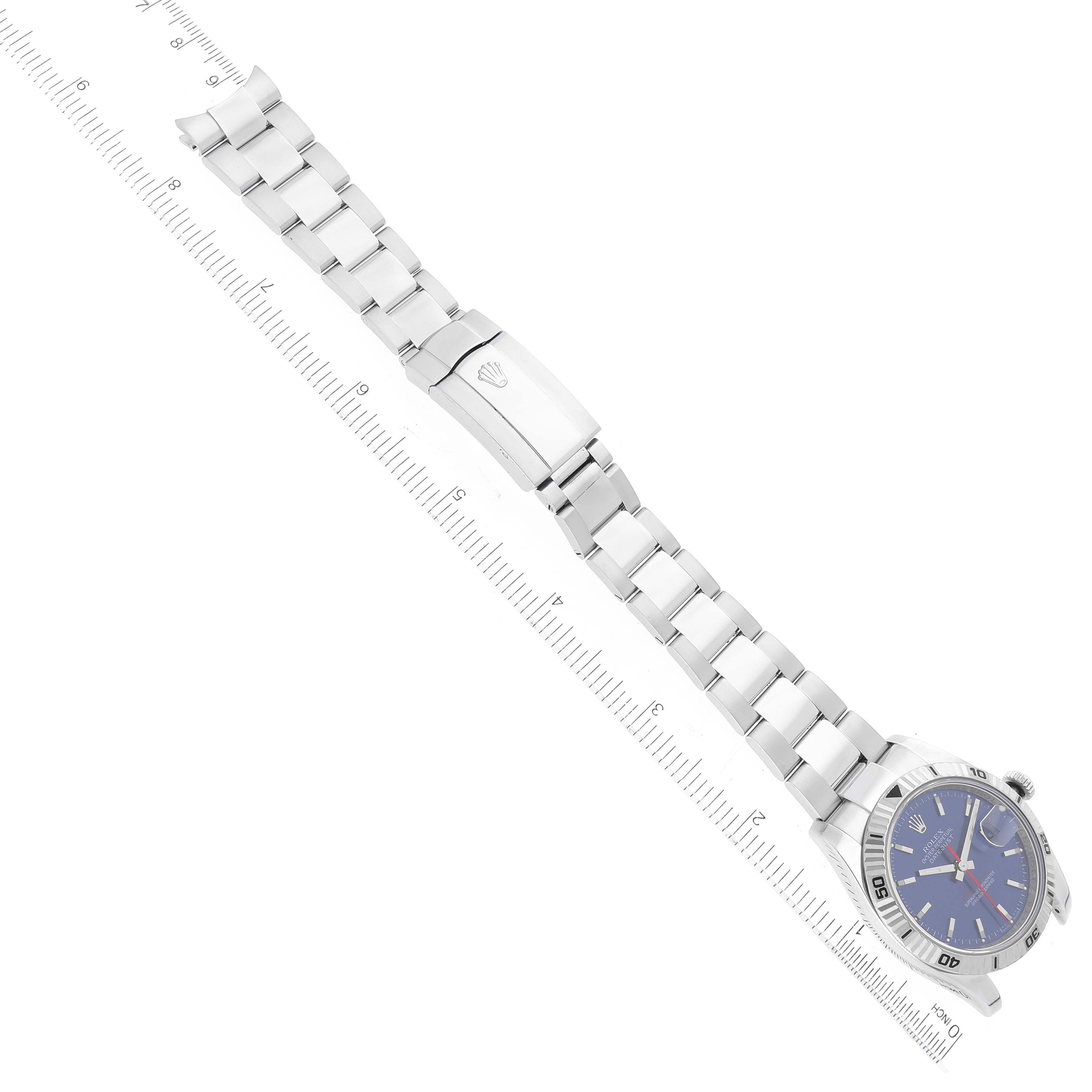 This image shows a top view of a Rolex Turn-o-Graph 116264 Men
s Stainless Steel Blue Dial 116264 Men
s Stainless Steel Blue Dial watch, showcasing its blue dial, bezel, bracelet, and clasp alongside a ruler.