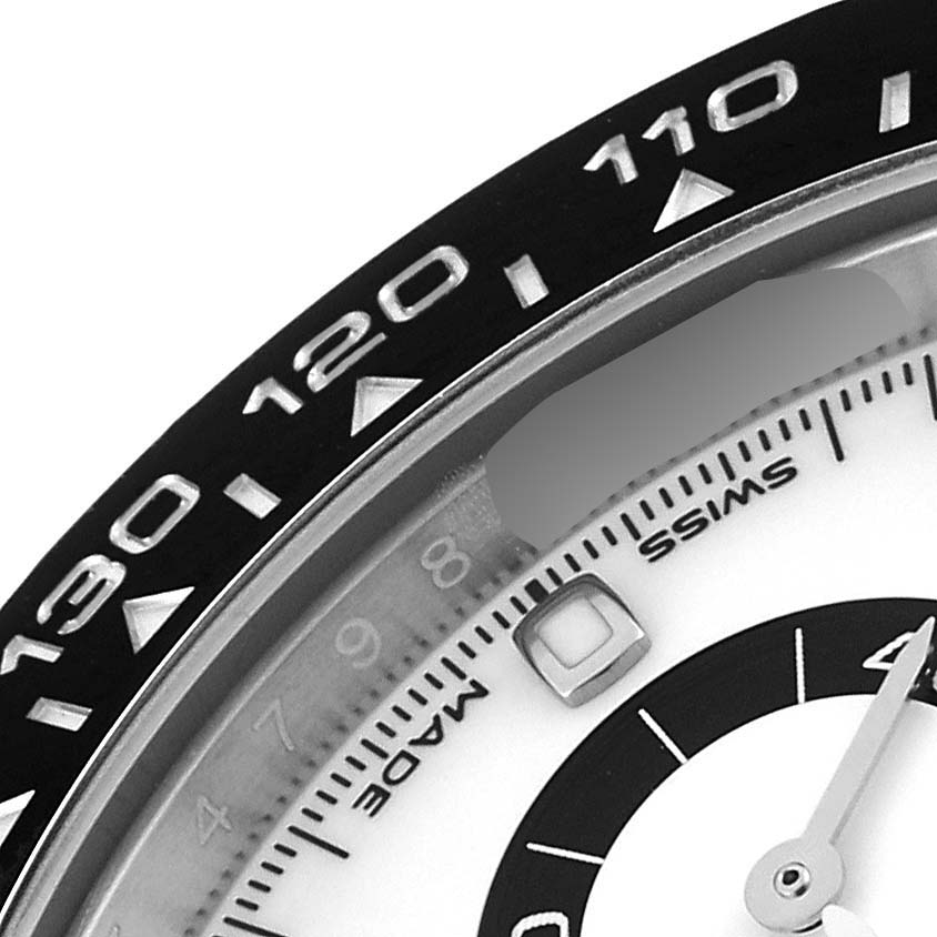 The image shows a close-up of the bezel and dial of the Rolex Daytona 116500 Men
s Stainless Steel White Dial 116500 Men
s Stainless Steel White Dial watch, emphasizing the upper left section.
