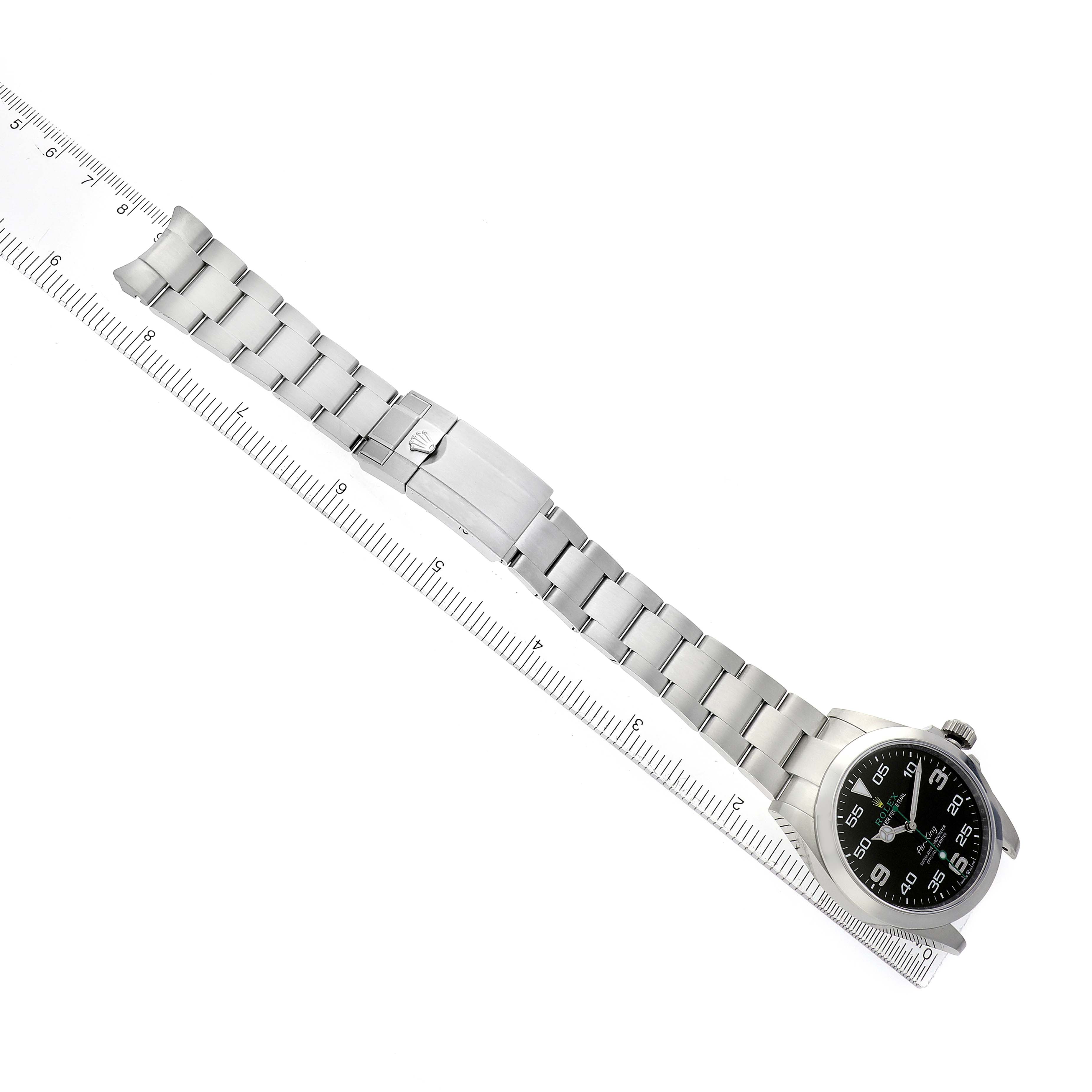 The image shows the Rolex Air-King model 126900 from a top-down angle, displaying the full stainless steel bracelet, clasp, and dial against a ruler for scale.