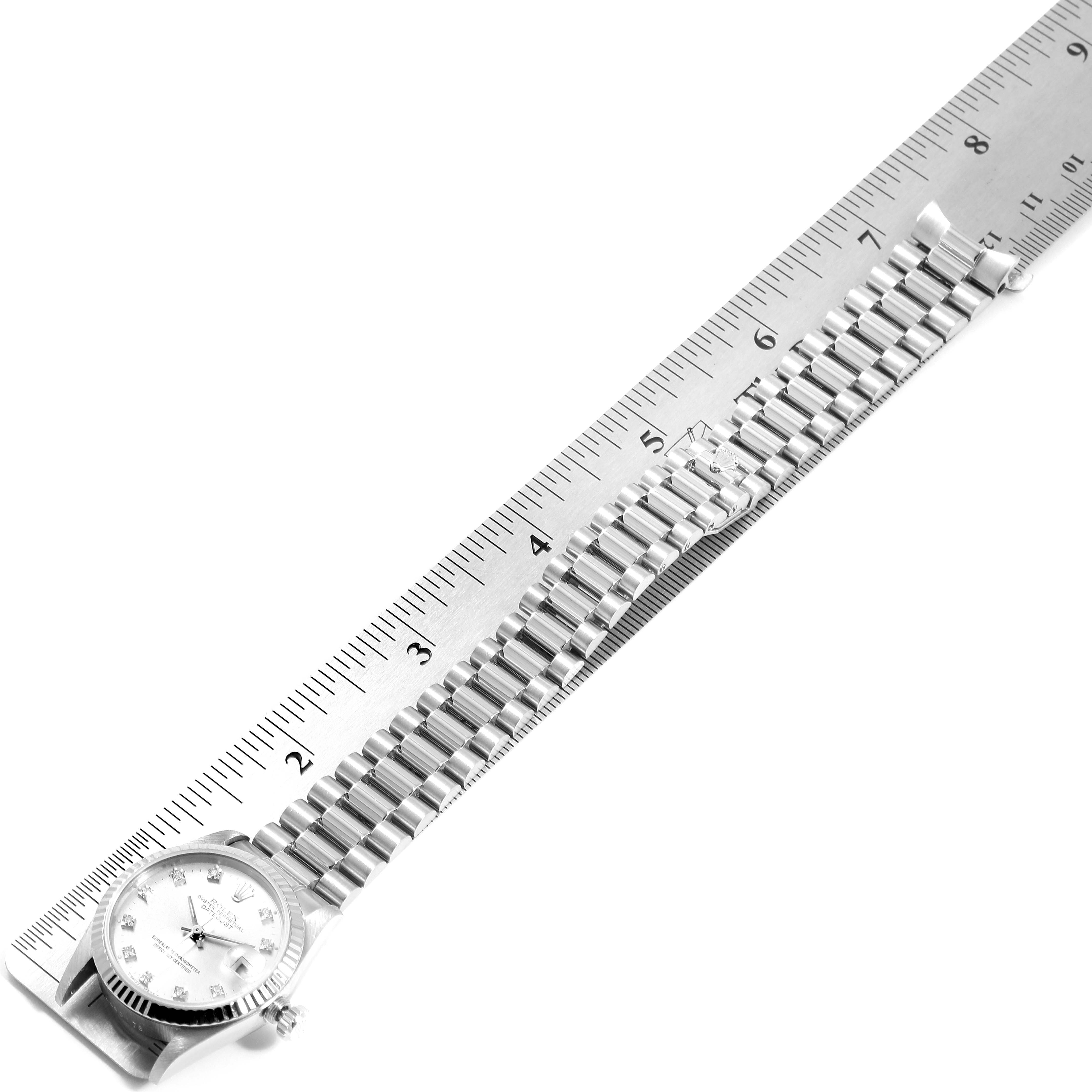 The image shows a Rolex President 68279 Women's White Gold Silver Dial 68279 Women's White Gold Silver Dial model watch laid flat, with its face and entire bracelet aligned next to a ruler.