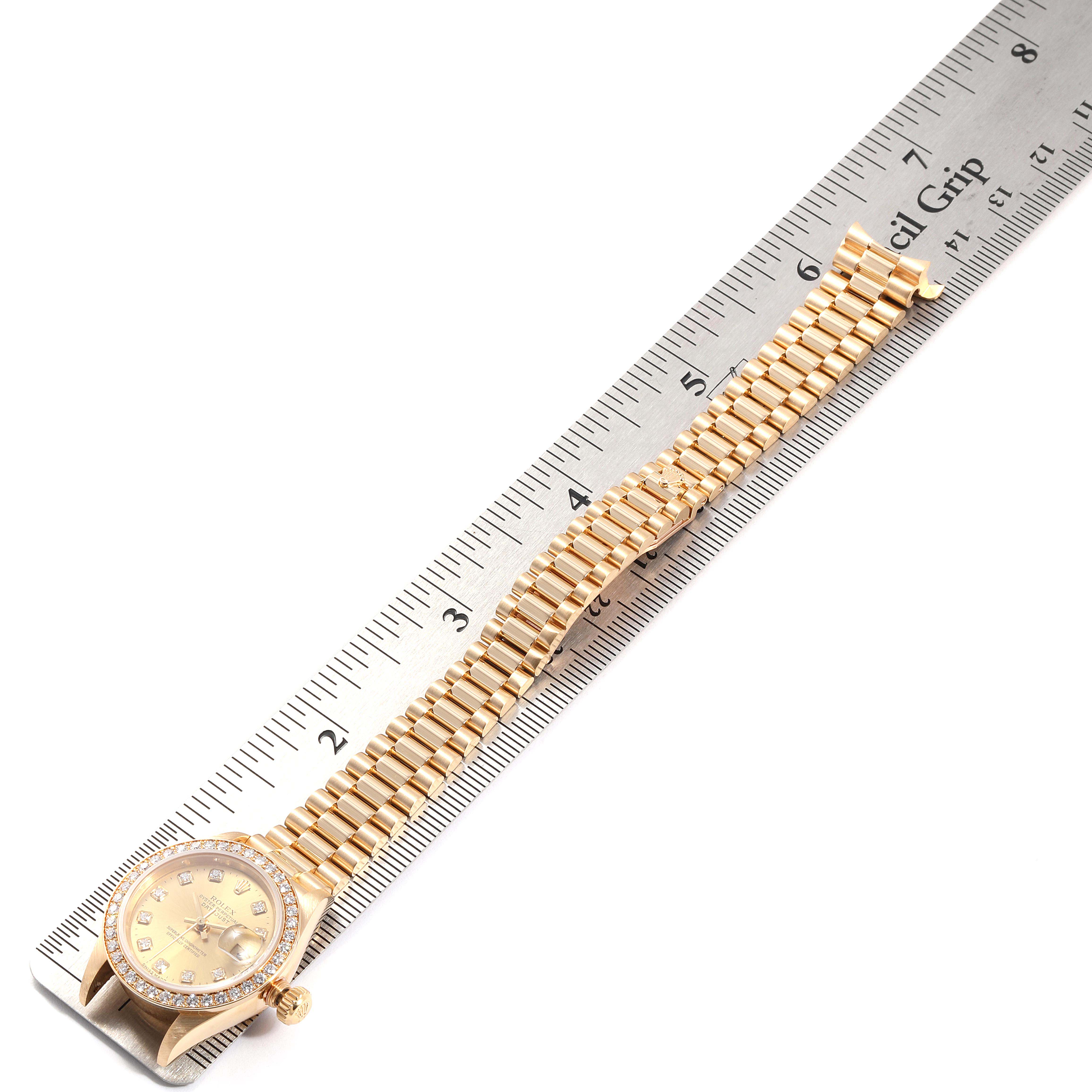This image shows the Rolex President 79178 Women
s Yellow Gold Champagne Dial 79178 Women
s Yellow Gold Champagne Dial model watch laid next to a ruler, displaying the watch face and full bracelet.