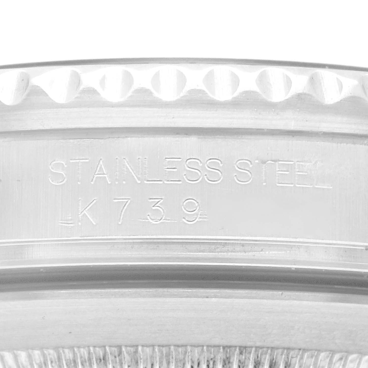 The image shows a close-up of the side of a Rolex Submariner model 16610, focusing on the watch
s stainless steel bezel with partial engravings visible.
