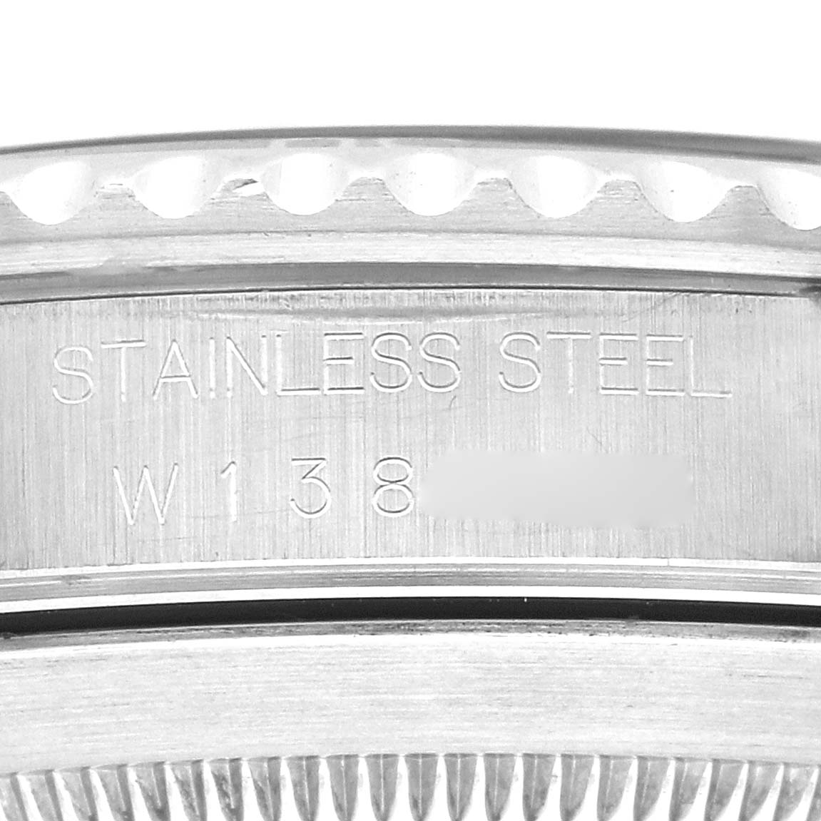 The image shows a close-up of the engraved side of the Rolex Submariner model 14060, focusing on the "Stainless Steel" text and part of the case edge.