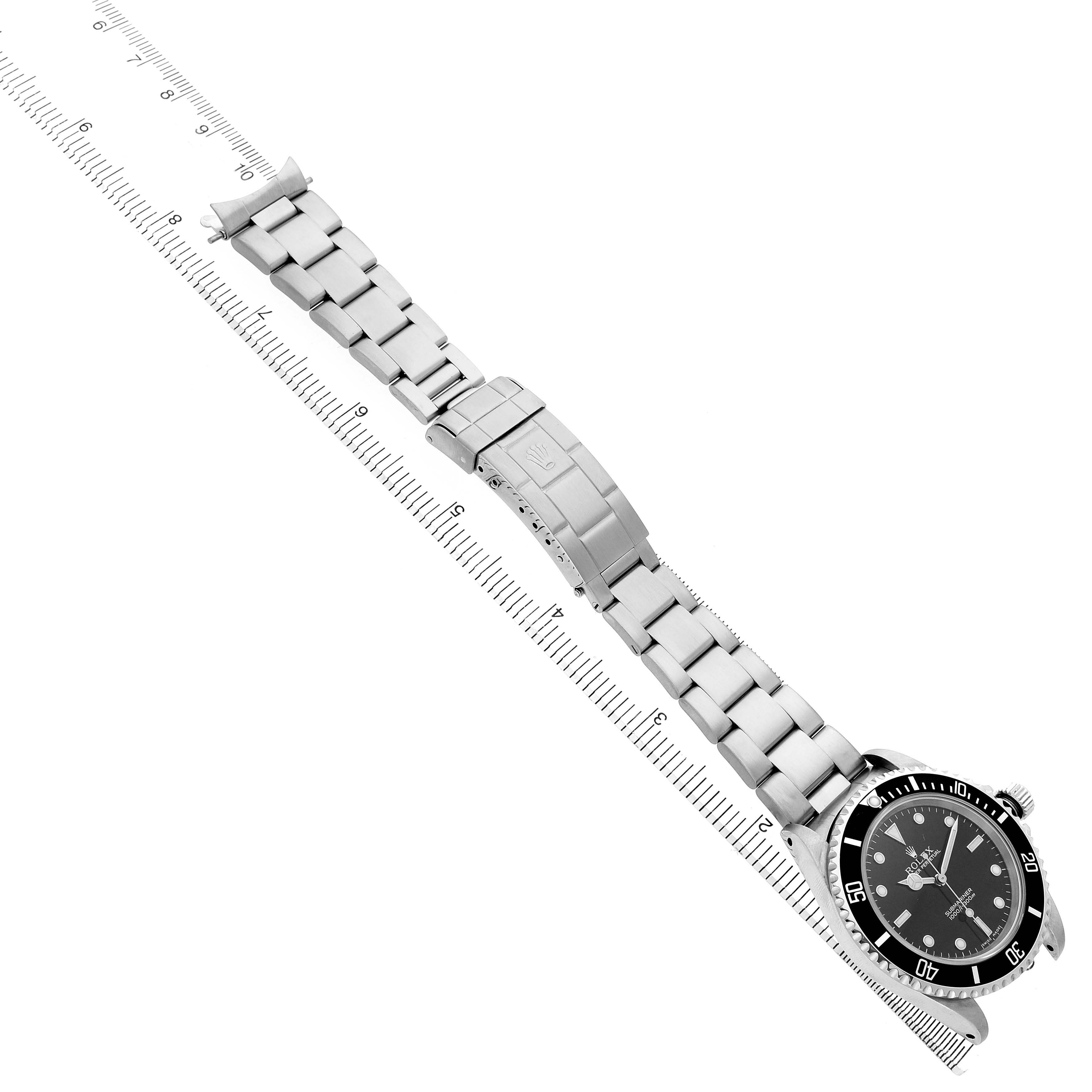 The image shows a Rolex Submariner 14060 Men's Stainless Steel Black Dial watch laid flat, highlighting its bracelet and clasp at an angle along a measuring ruler.
