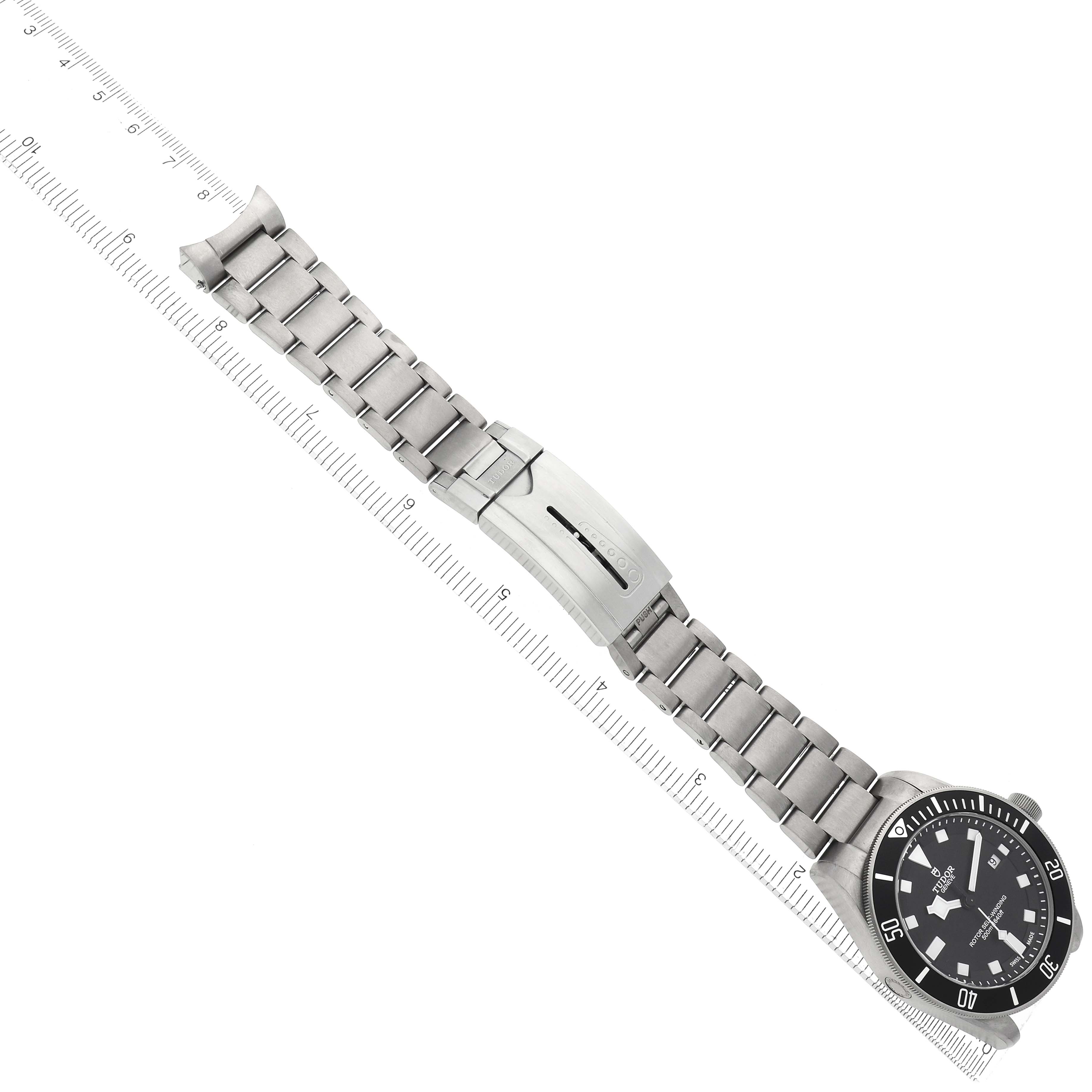 The image shows a Tudor Pelagos model 25500TN men
s watch with a metal bracelet and clasp, viewed from above, aligned with a ruler measuring its length.