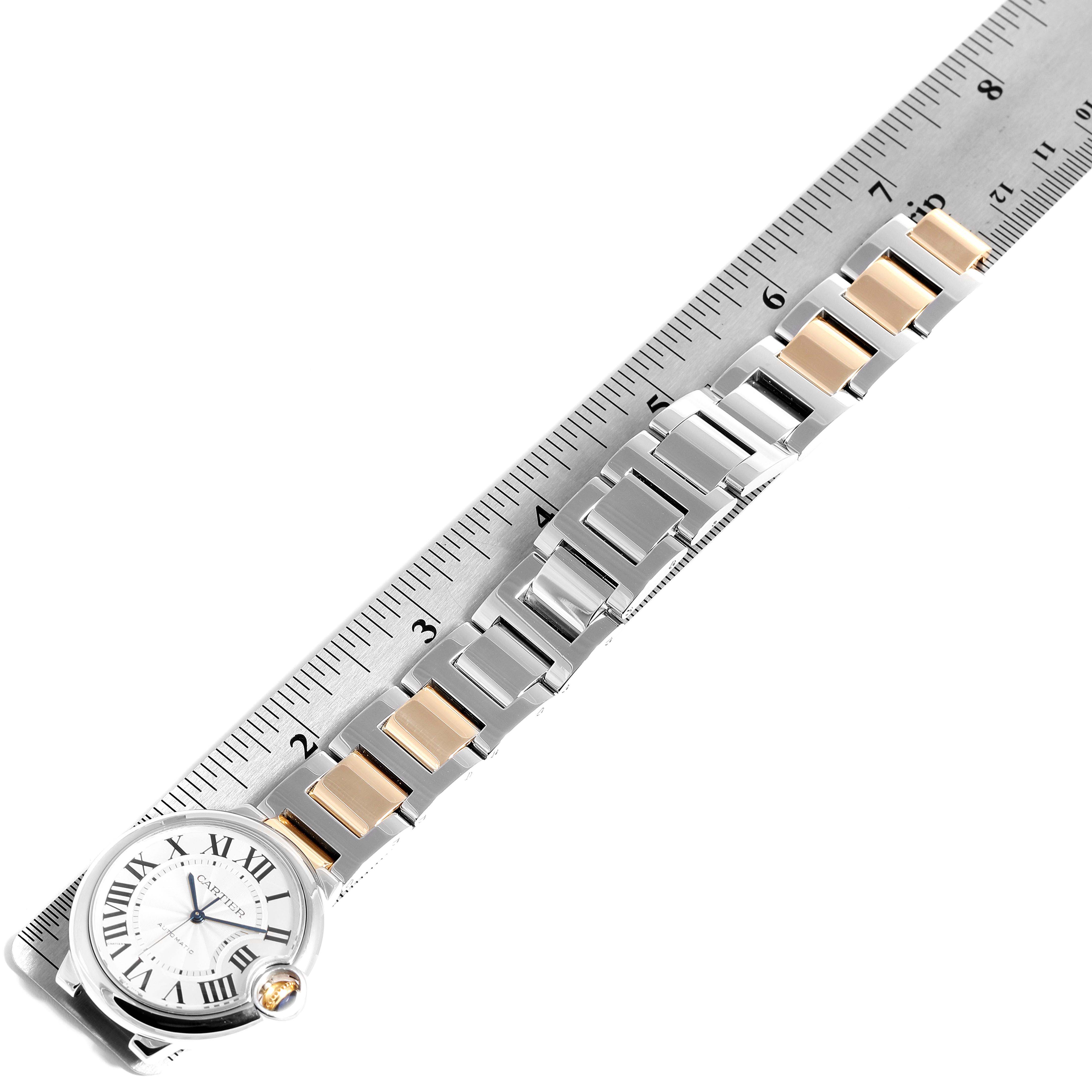 The image shows a top-down view of a Cartier Ballon Bleu W2BB0012 Women
s Steel and Gold (two tone) Silver Dial W2BB0012 Women
s Steel and Gold (two tone) Silver Dial watch with its two-tone metal bracelet measured against a ruler.