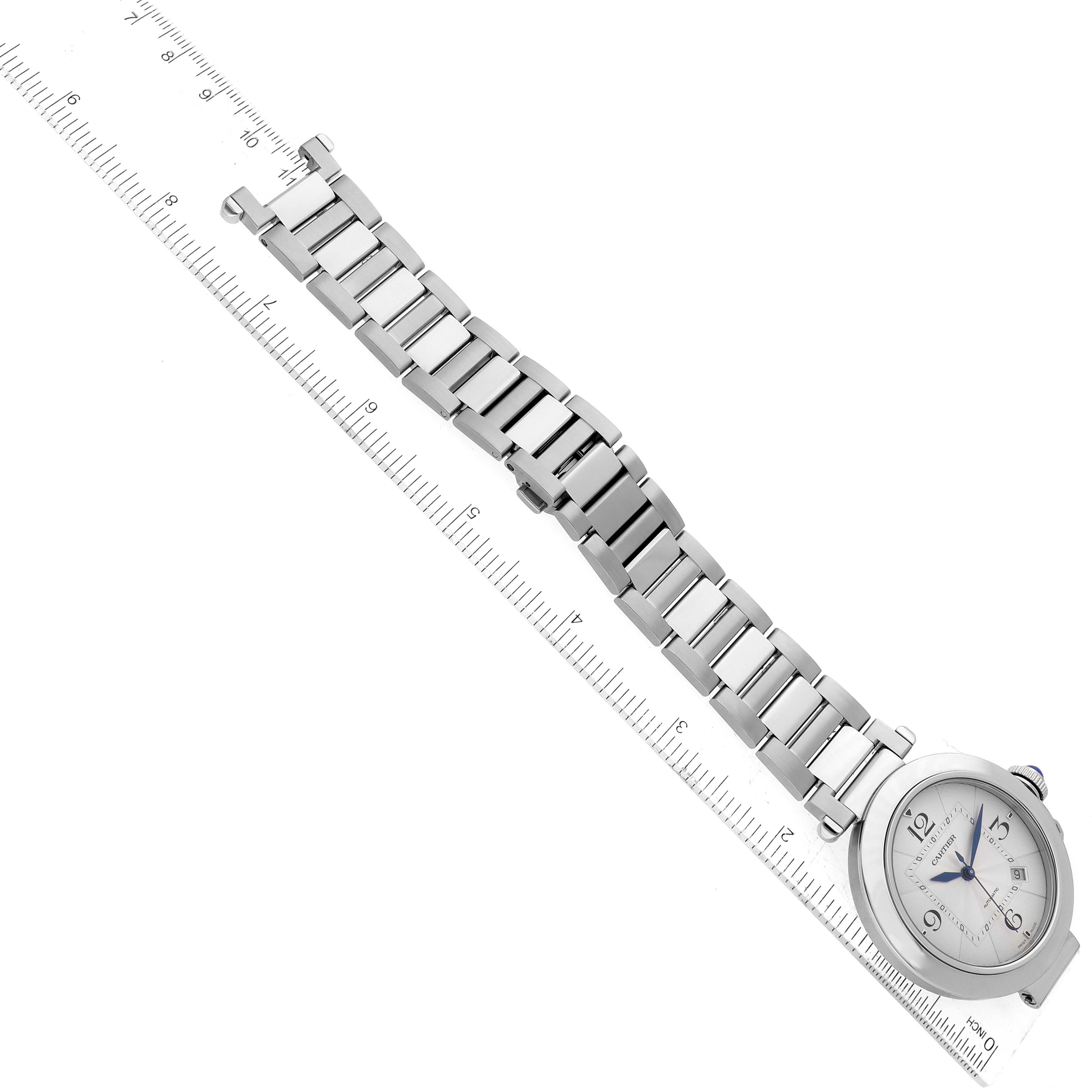 The image shows a Cartier Pasha WSPA0009 Men's Stainless Steel Silver Dial WSPA0009 Men's Stainless Steel Silver Dial model watch laid diagonally along a ruler, displaying the face and entire bracelet.