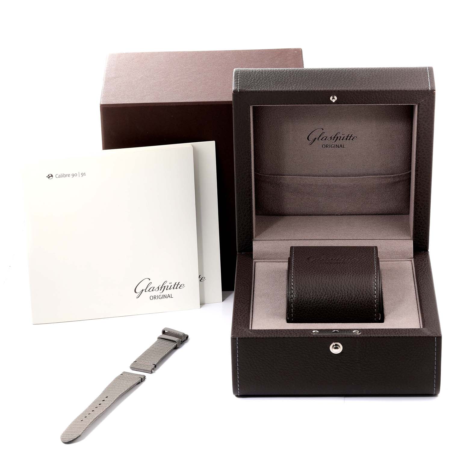 The image shows the packaging, watch strap, and user manual for a Glashütte Original Pano model.