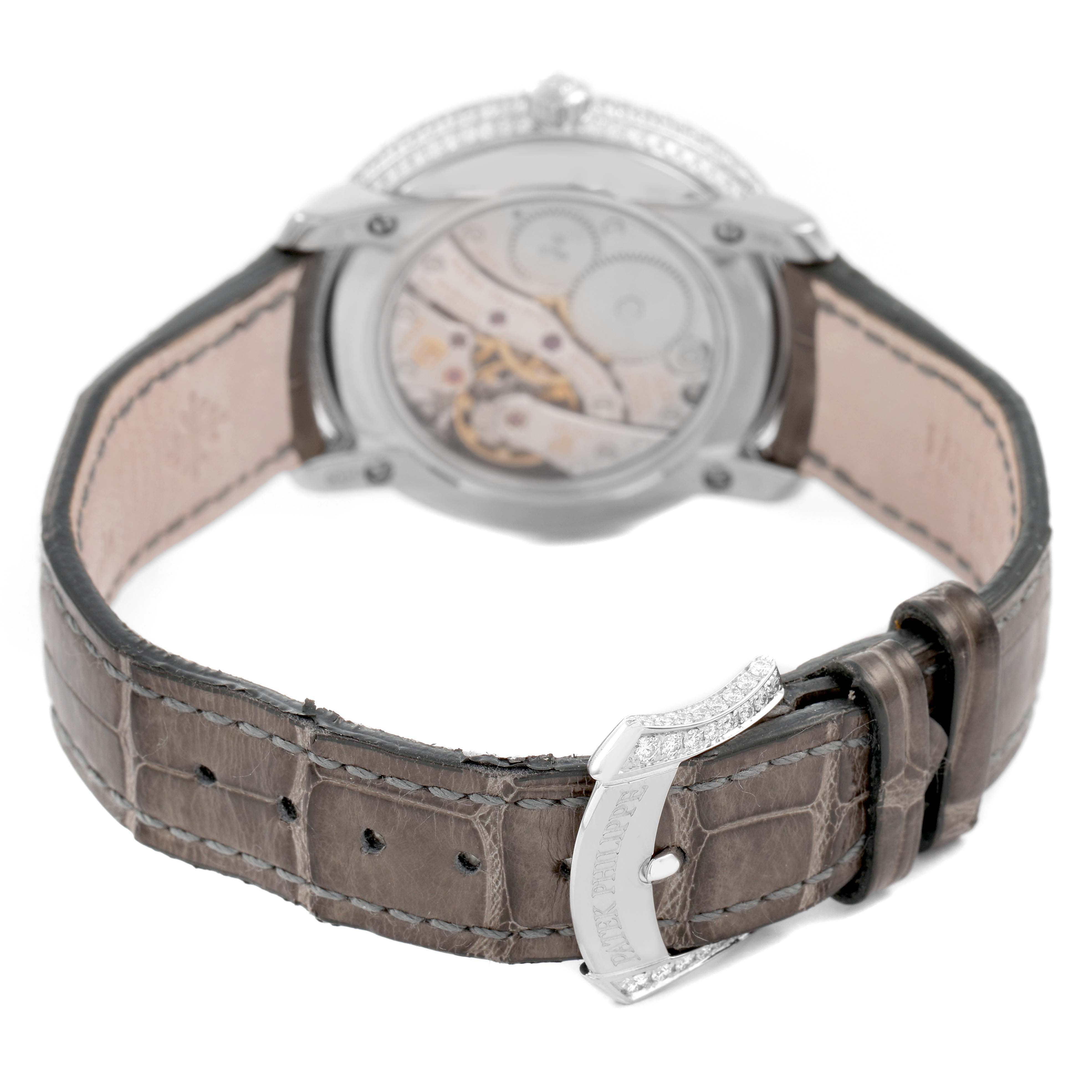 The image shows the rear view of a Patek Philippe Complications 4968G Women's White Gold Mother of Pearl Dial watch, highlighting its movement and clasp on a leather strap.