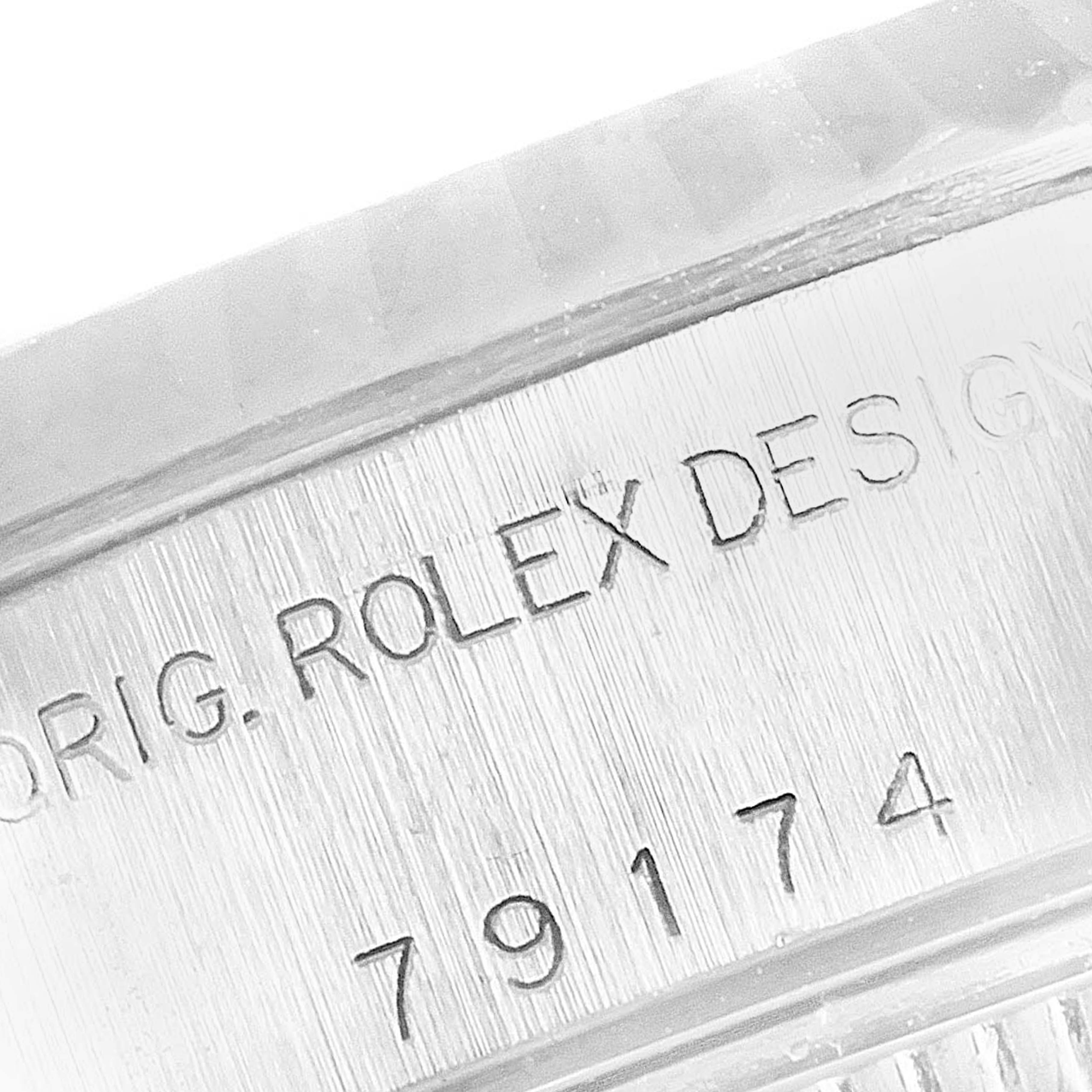 The image shows an angled close-up of the case side of a Rolex Datejust 79174 Women
s Stainless Steel Silver Dial 79174 Women
s Stainless Steel Silver Dial model, displaying part of the serial number and engraving.