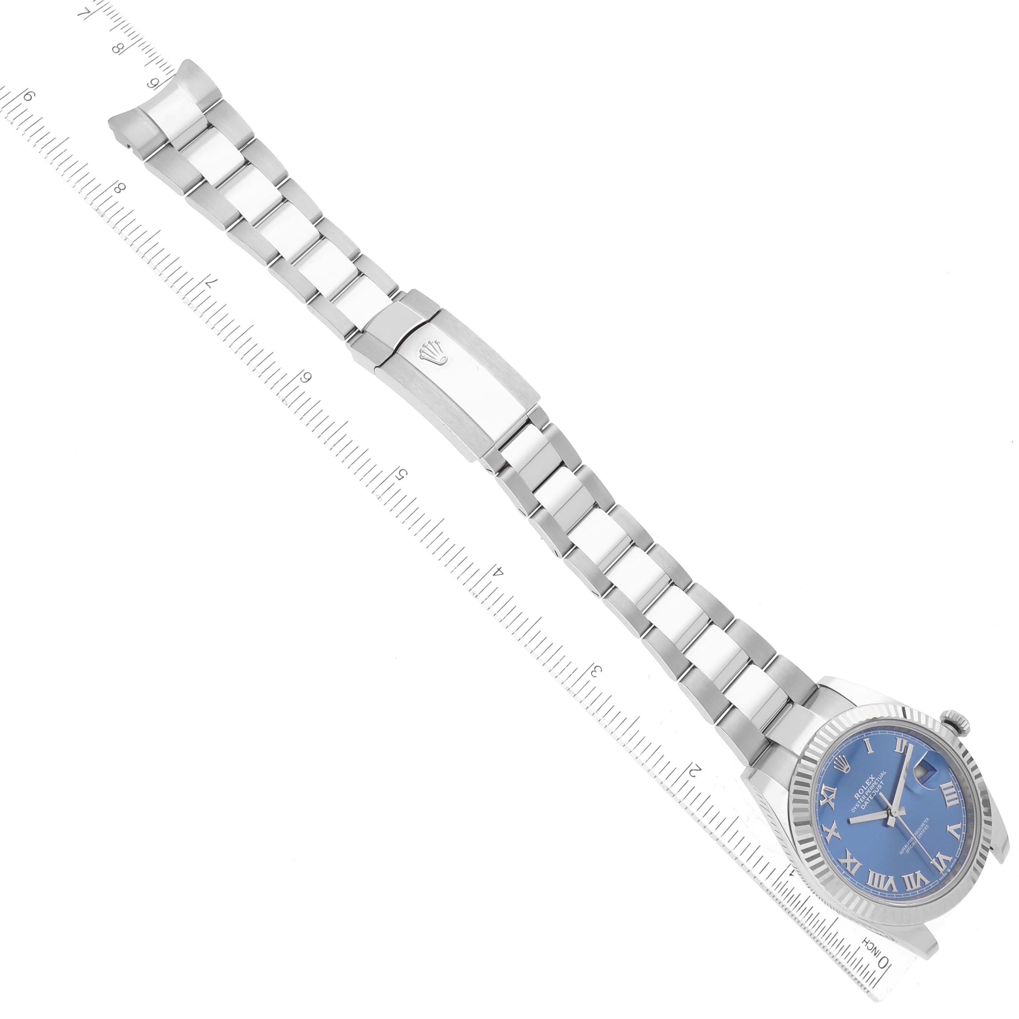 The Rolex Datejust 41 126334 Men's Stainless Steel Blue Dial is shown from a top view, highlighting the blue dial, fluted bezel, and stainless steel bracelet next to a ruler.