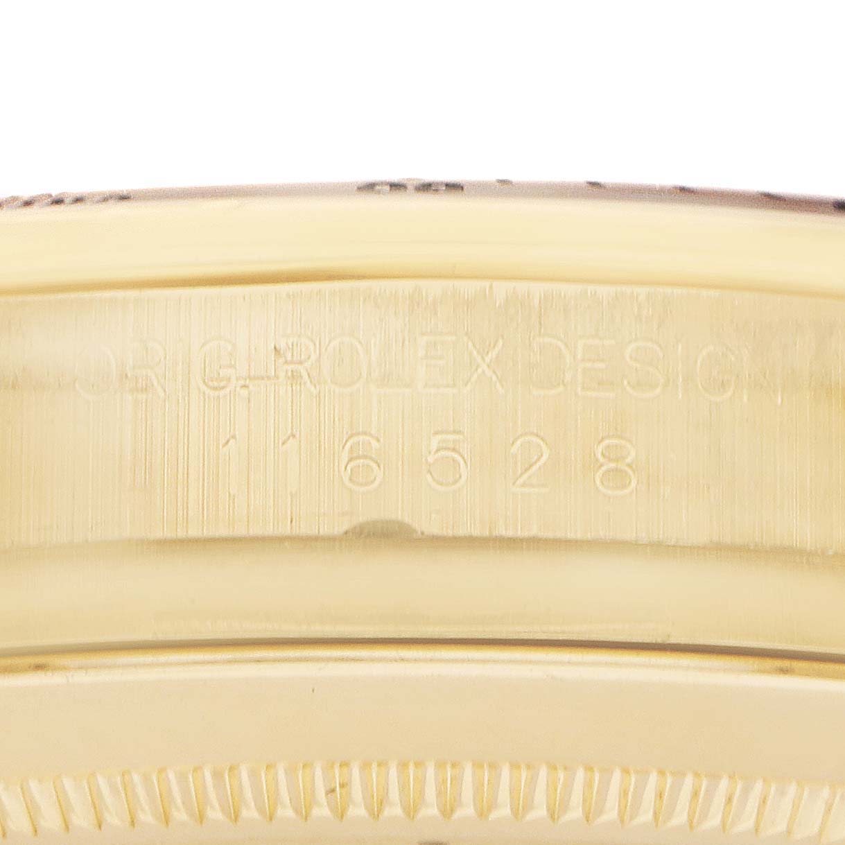 The image shows a close-up of the edge of a Rolex Daytona model 116528, focusing on the engraved model number on the case.