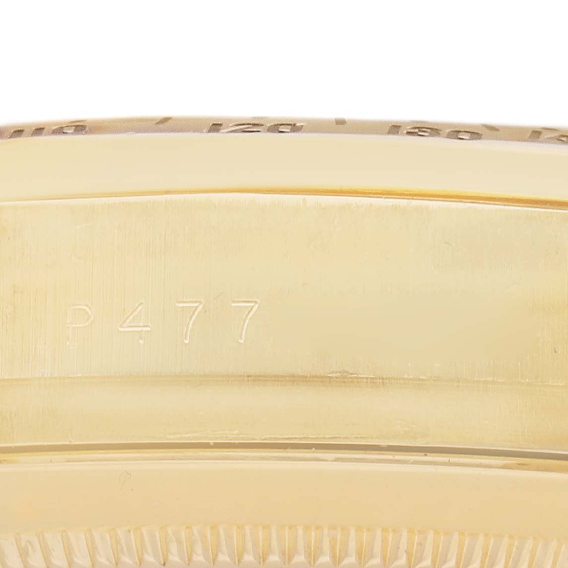 The image shows a close-up side angle of the Rolex Daytona model 116528, highlighting the gold case and engraved markings.