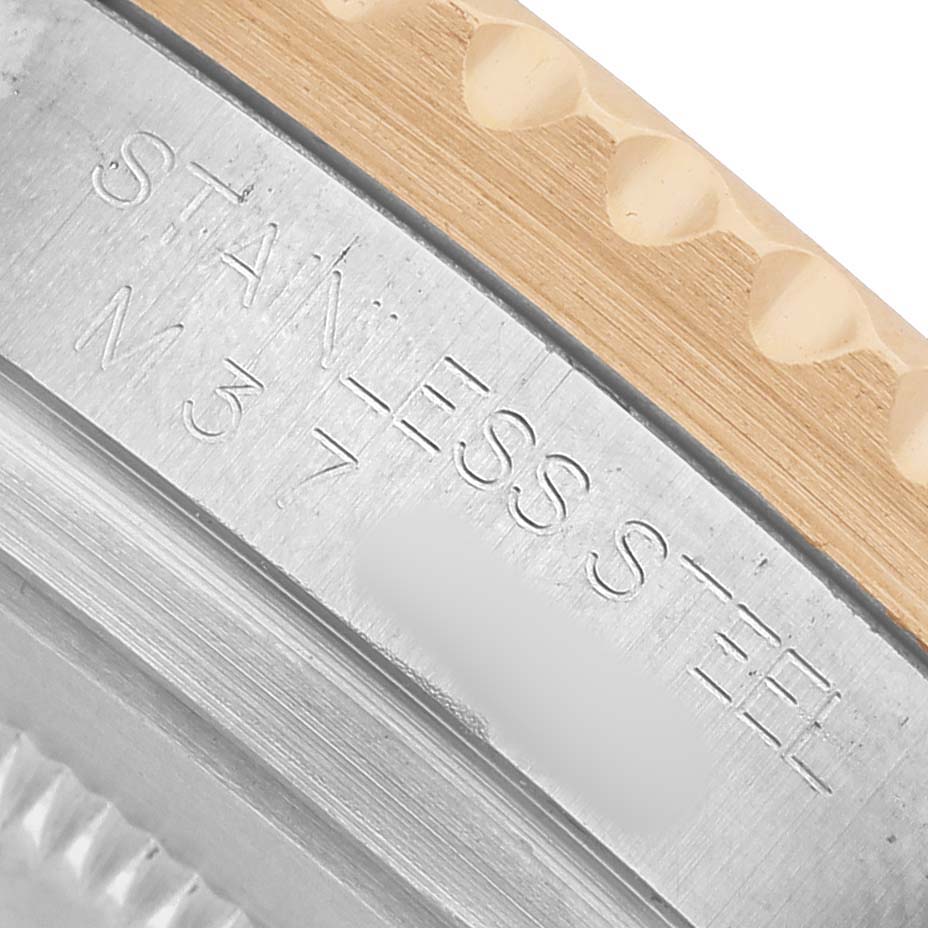 The image shows a close-up of the side of a Rolex GMT-Master 116713 Men's Steel and Gold (two tone) Black Dial, highlighting the engraved "STAINLESS STEEL" text on the case.